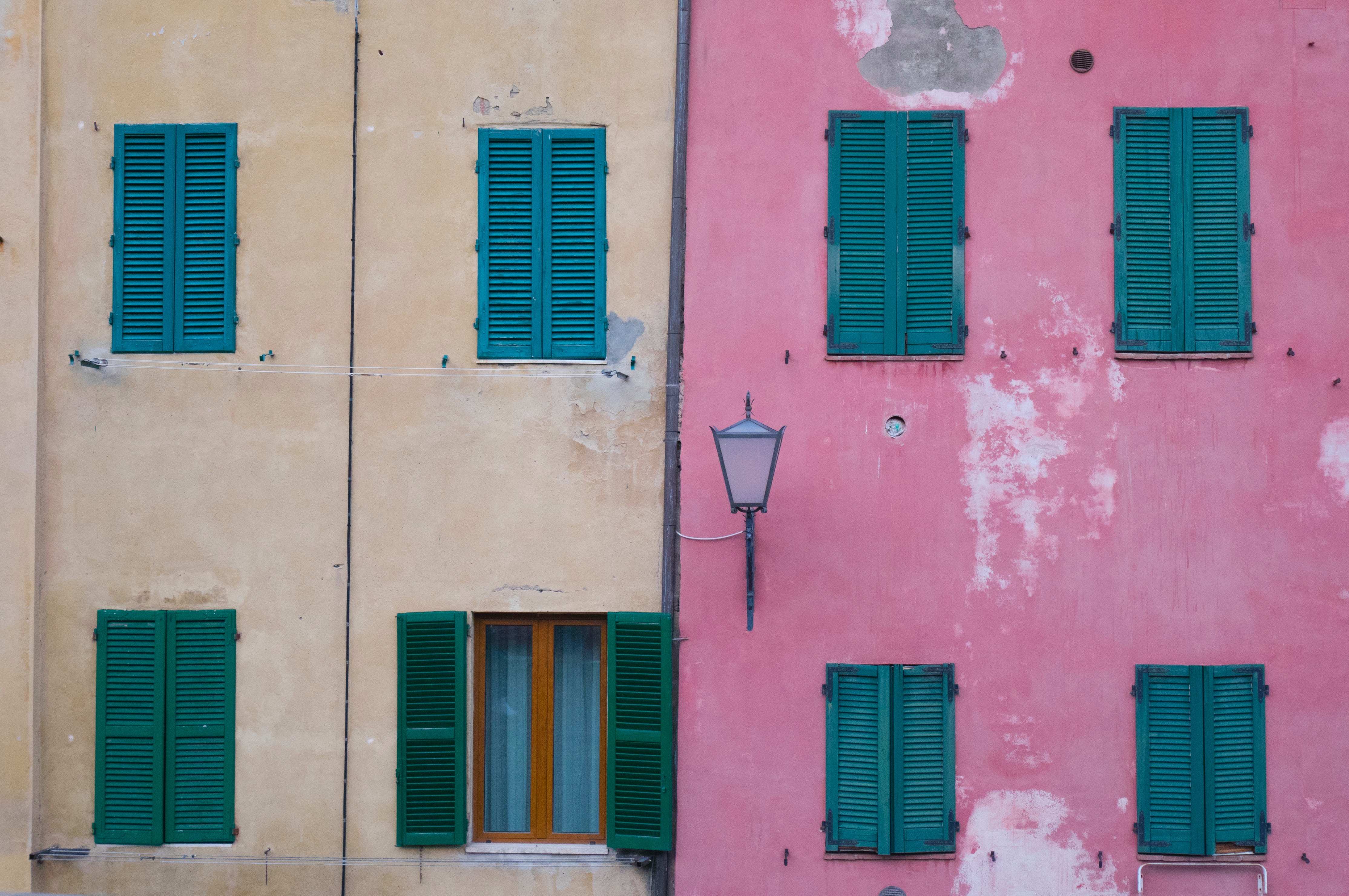 Two buildings with colorful facades and green shutters HD Wallpaper