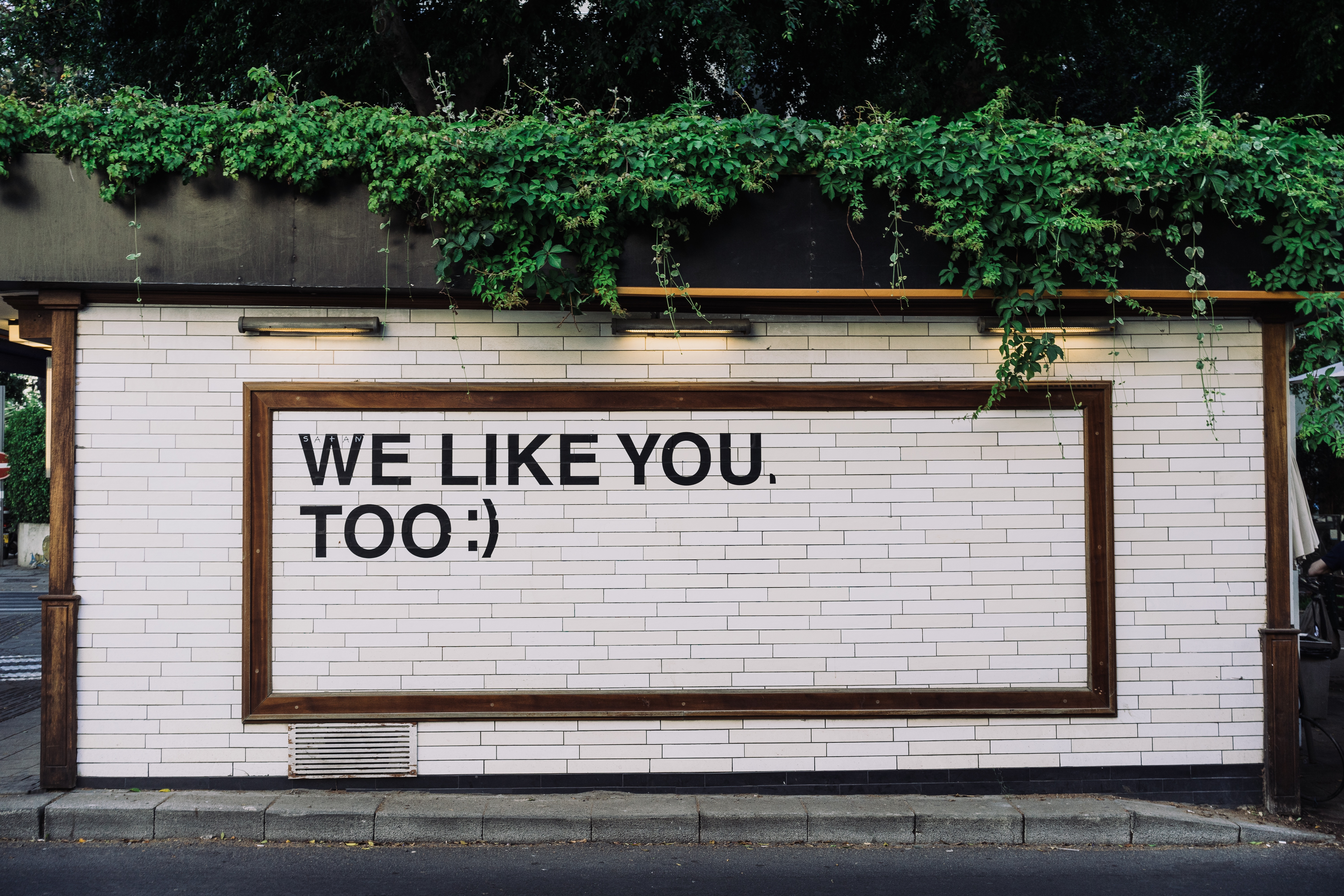 White brick wall with "WE LIKE YOU. TOO:)" text HD Wallpaper