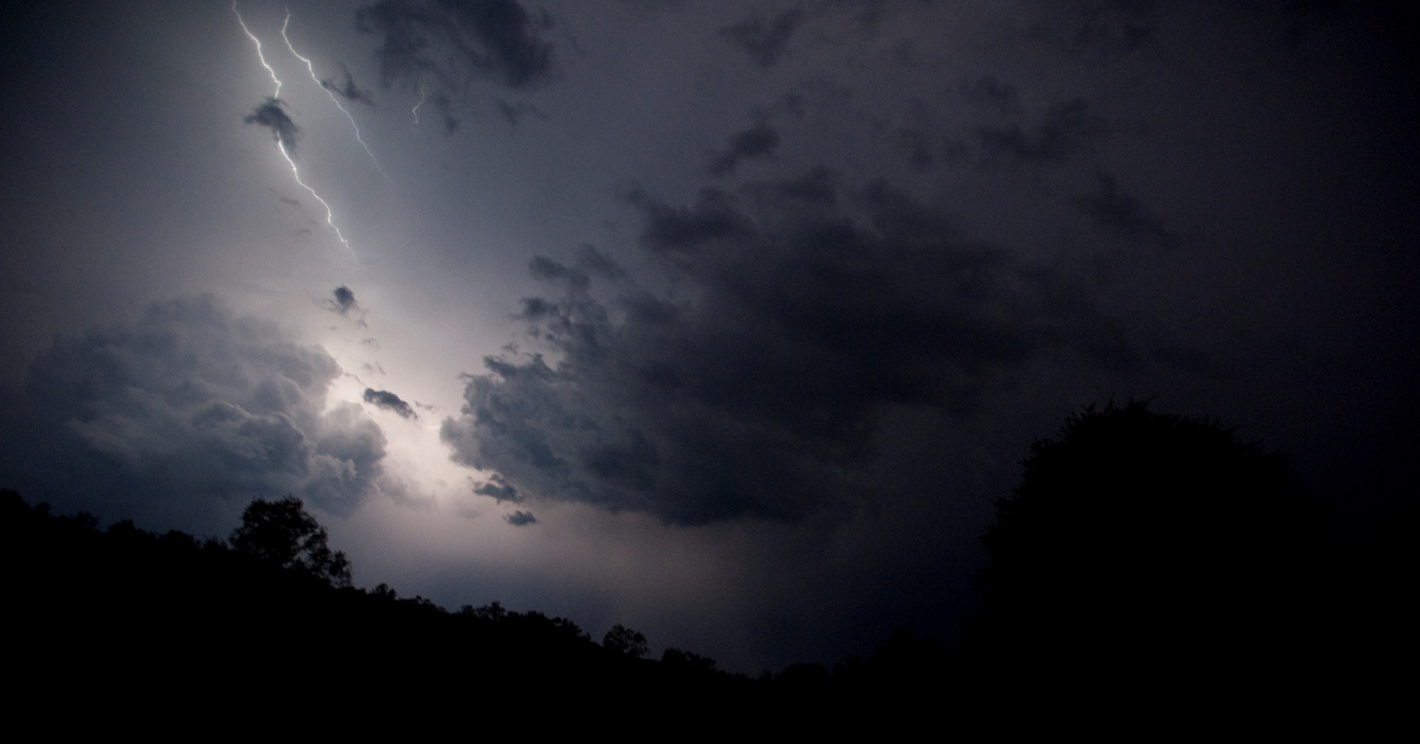 Lightning strike over dark clouds and trees at night HD Wallpaper