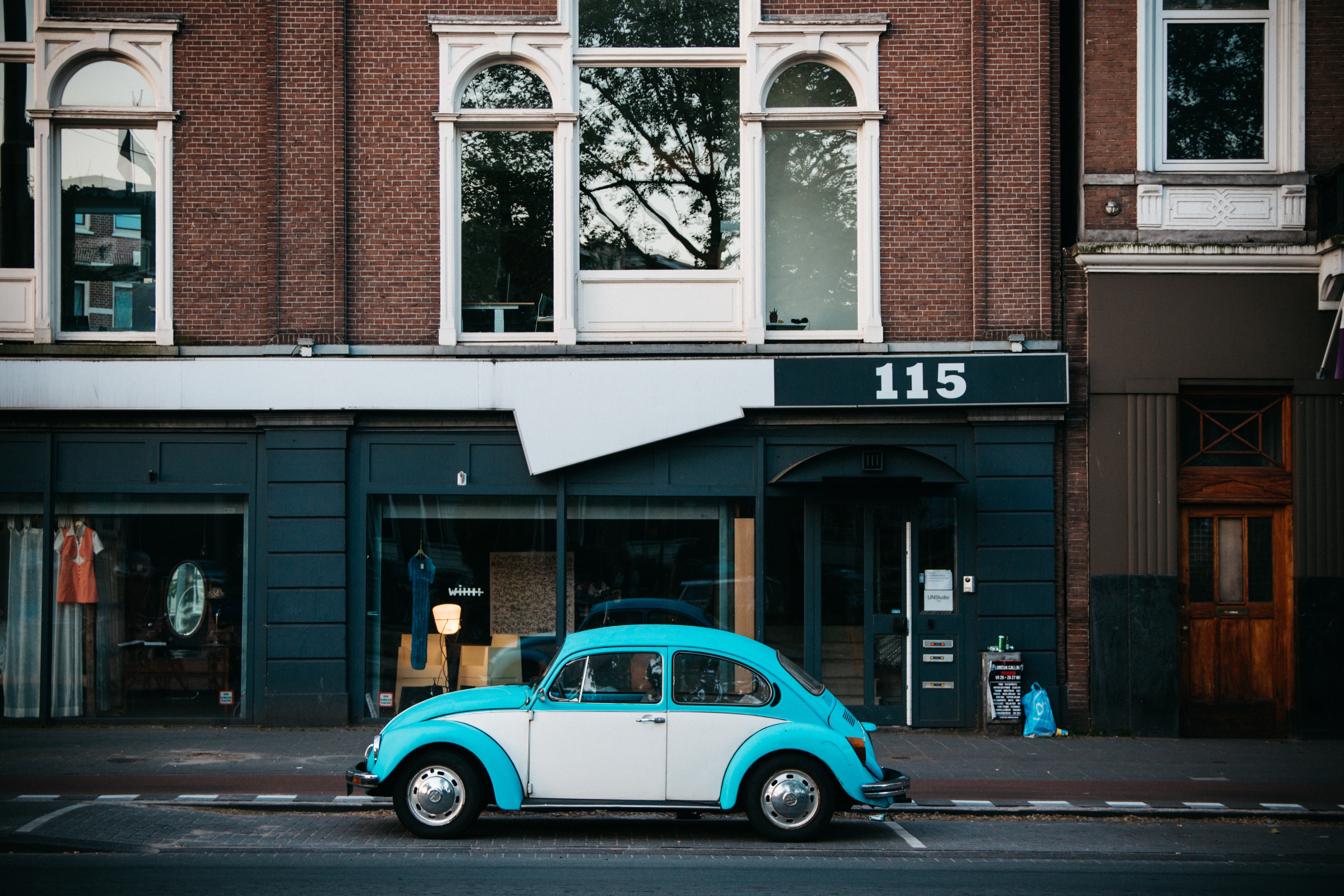 Blue and white Volkswagen Beetle parked in front of store 115 HD Wallpaper