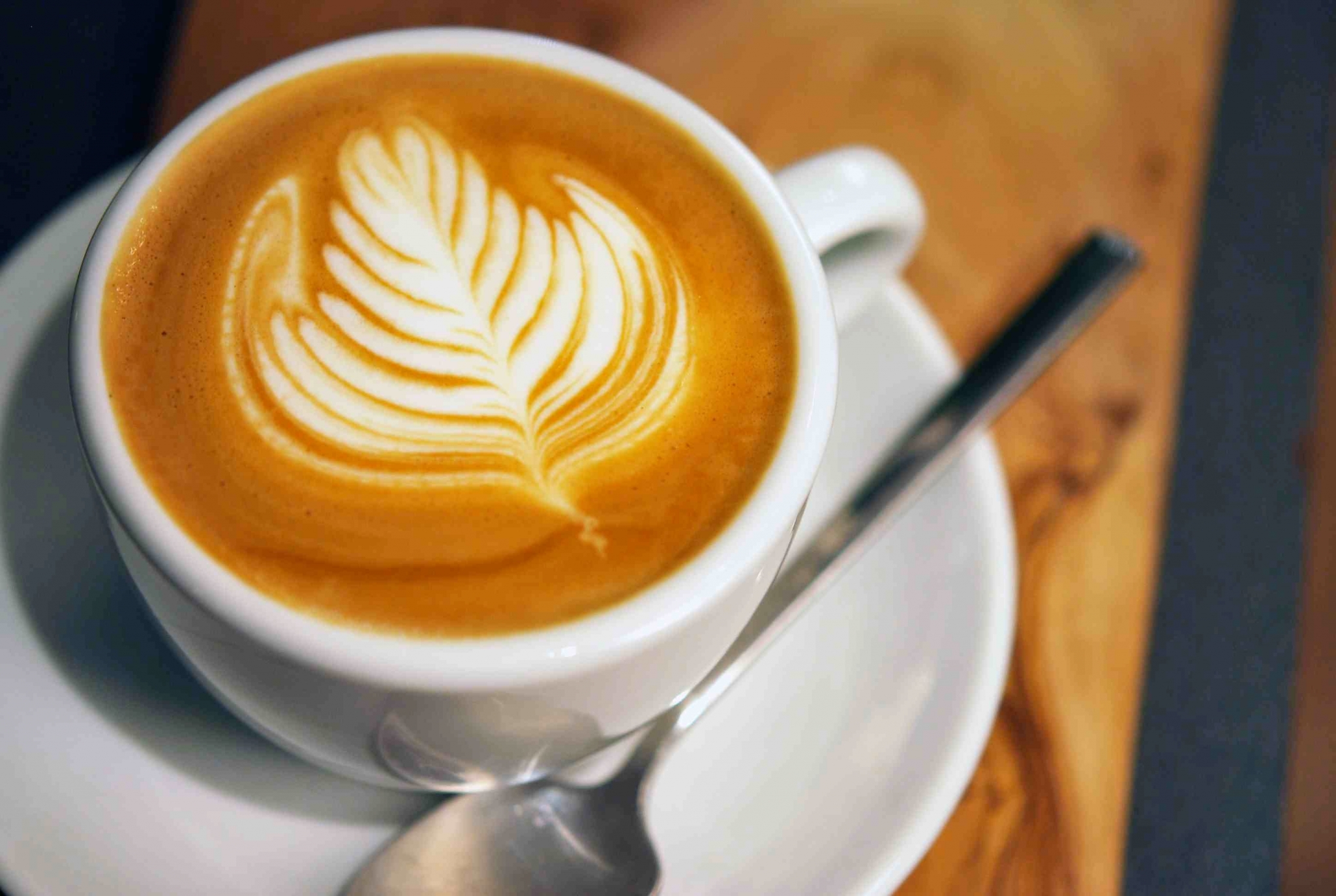 Latte art coffee in a white cup with a spoon HD Wallpaper