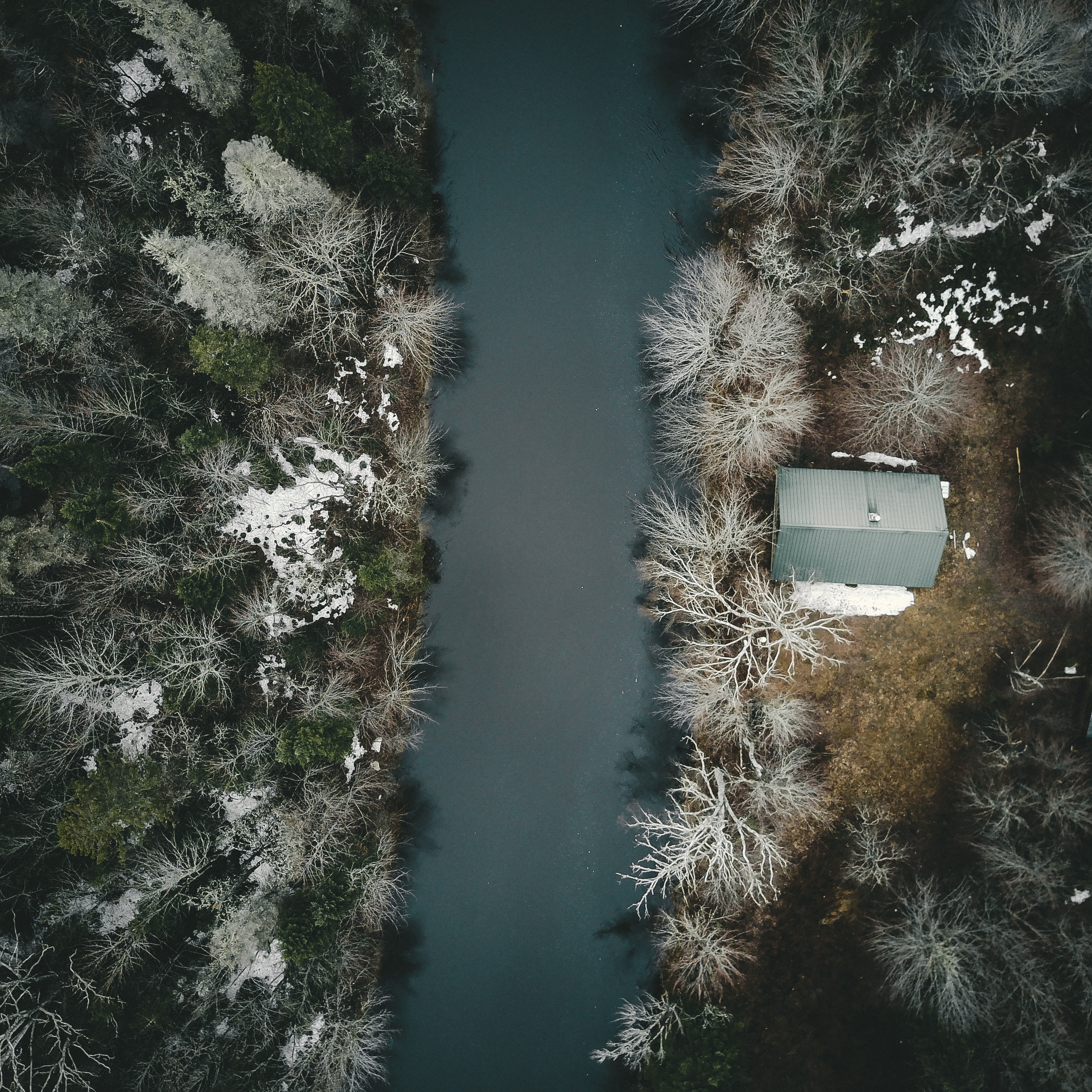Aerial view of a cabin by a river in winter HD Wallpaper