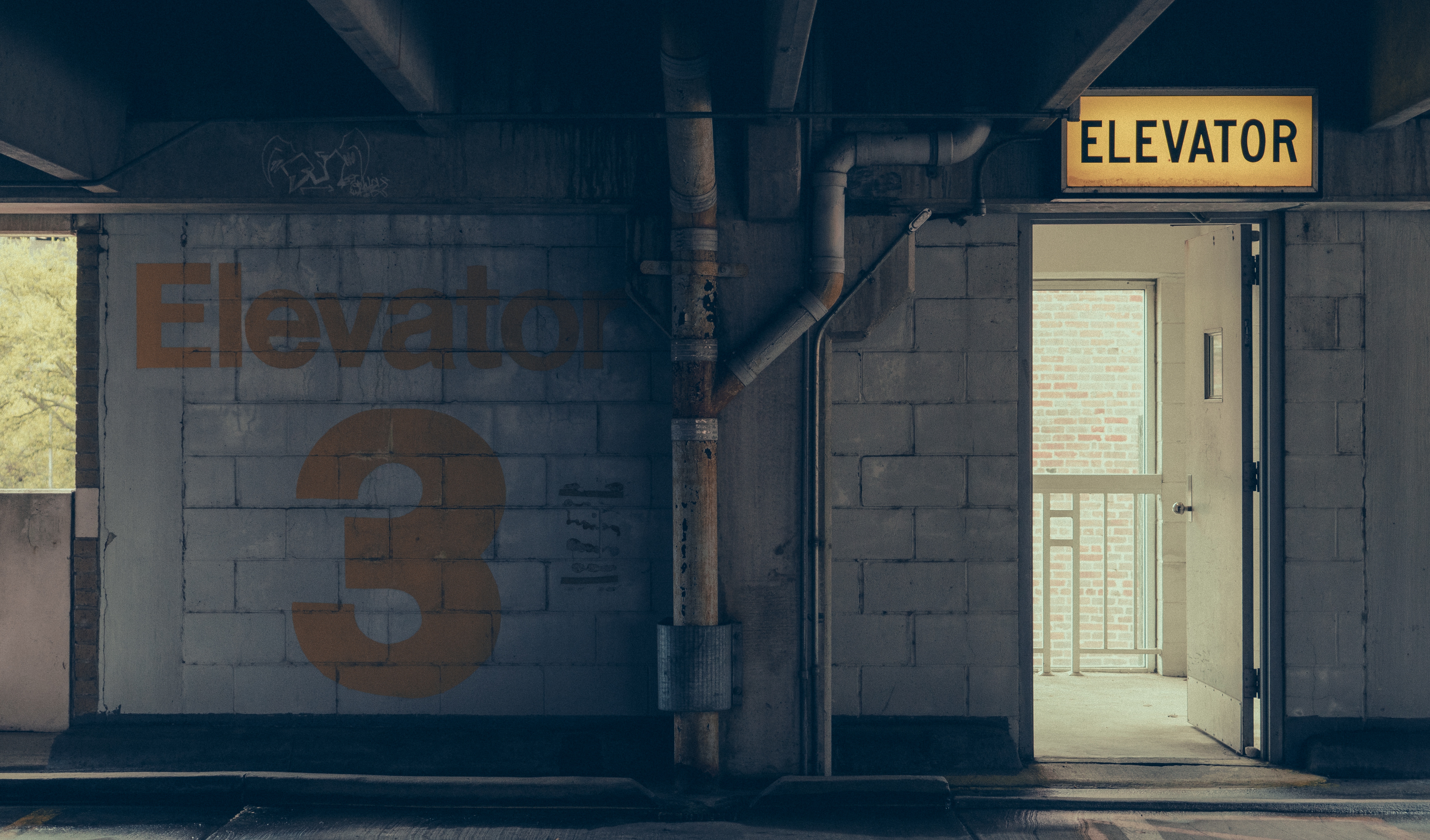 Elevator 3 sign and entrance in a concrete garage HD Wallpaper