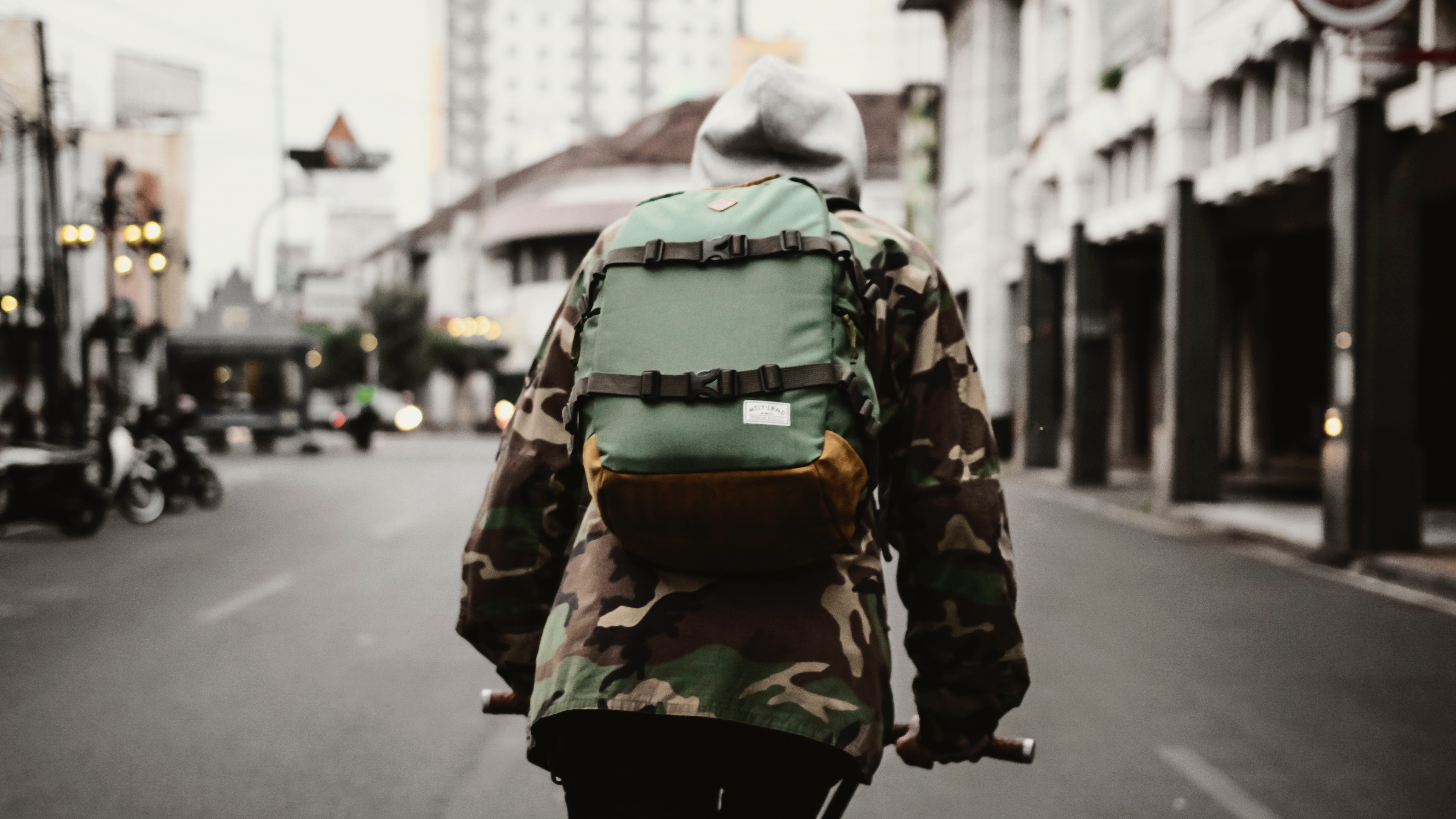 Person with backpack riding a bicycle in the city HD Wallpaper