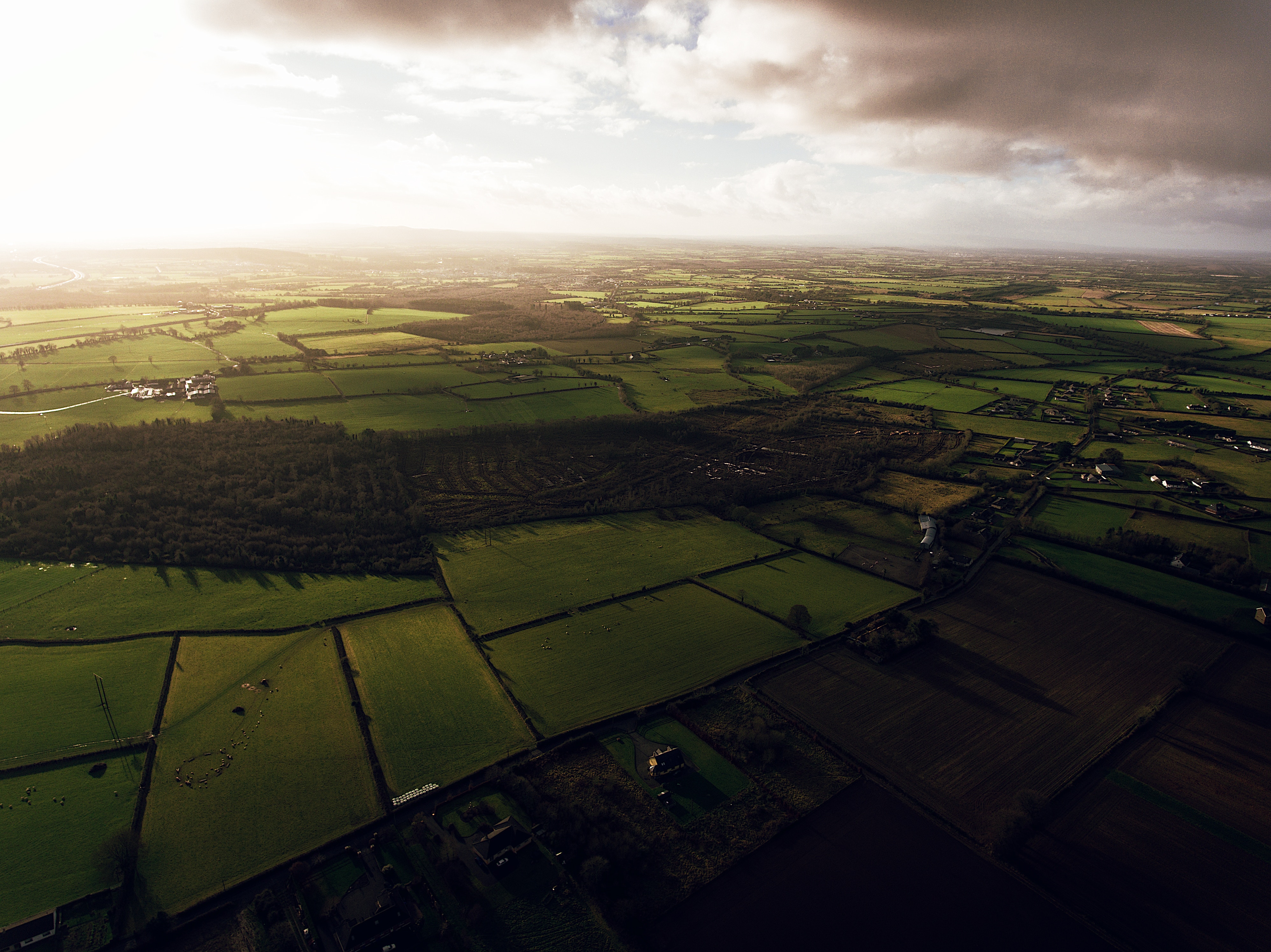 Aerial view of green patchwork fields in Ireland under an overcast sky HD Wallpaper