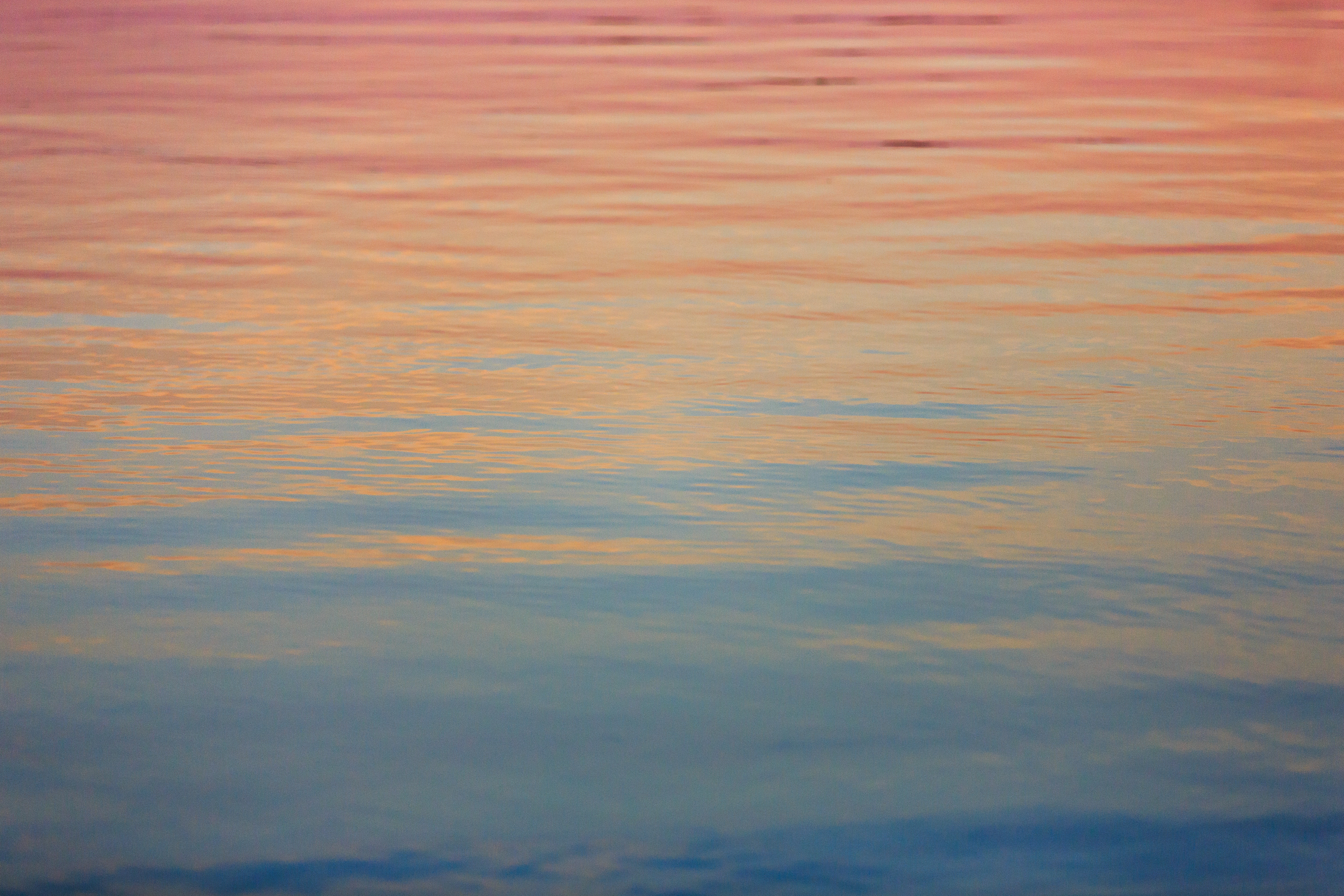 Water surface with ripples reflecting sunset colors HD Wallpaper