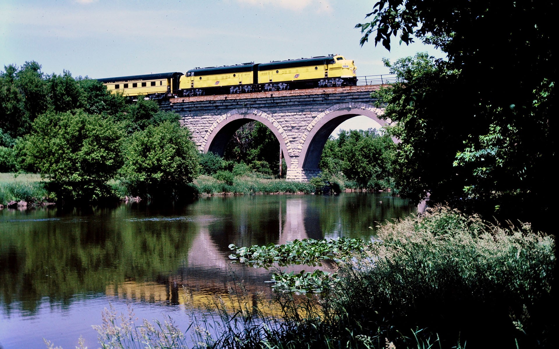 Yellow train on a stone bridge over a river HD Wallpaper