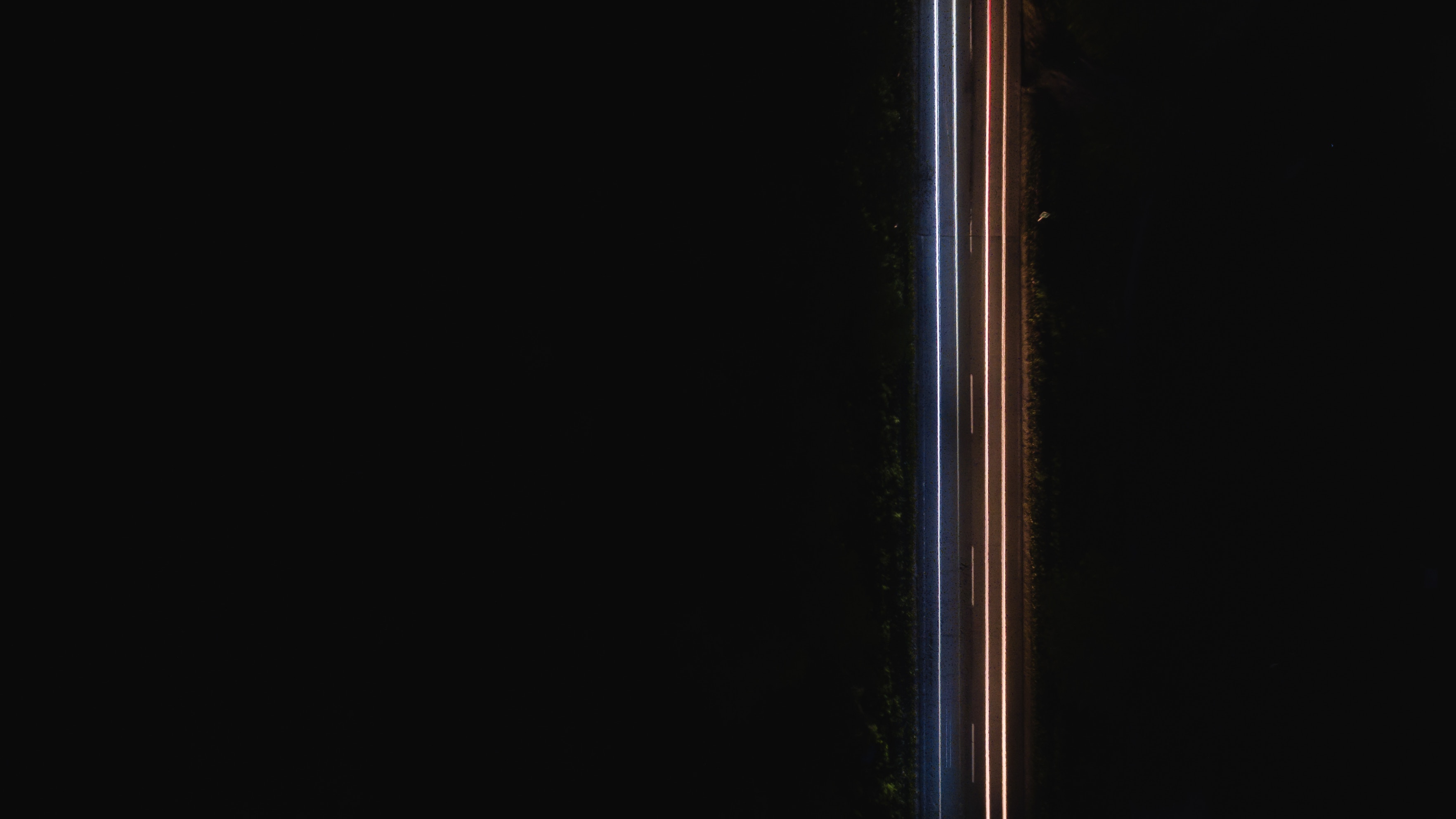 Aerial view of light trails on a dark road at night HD Wallpaper