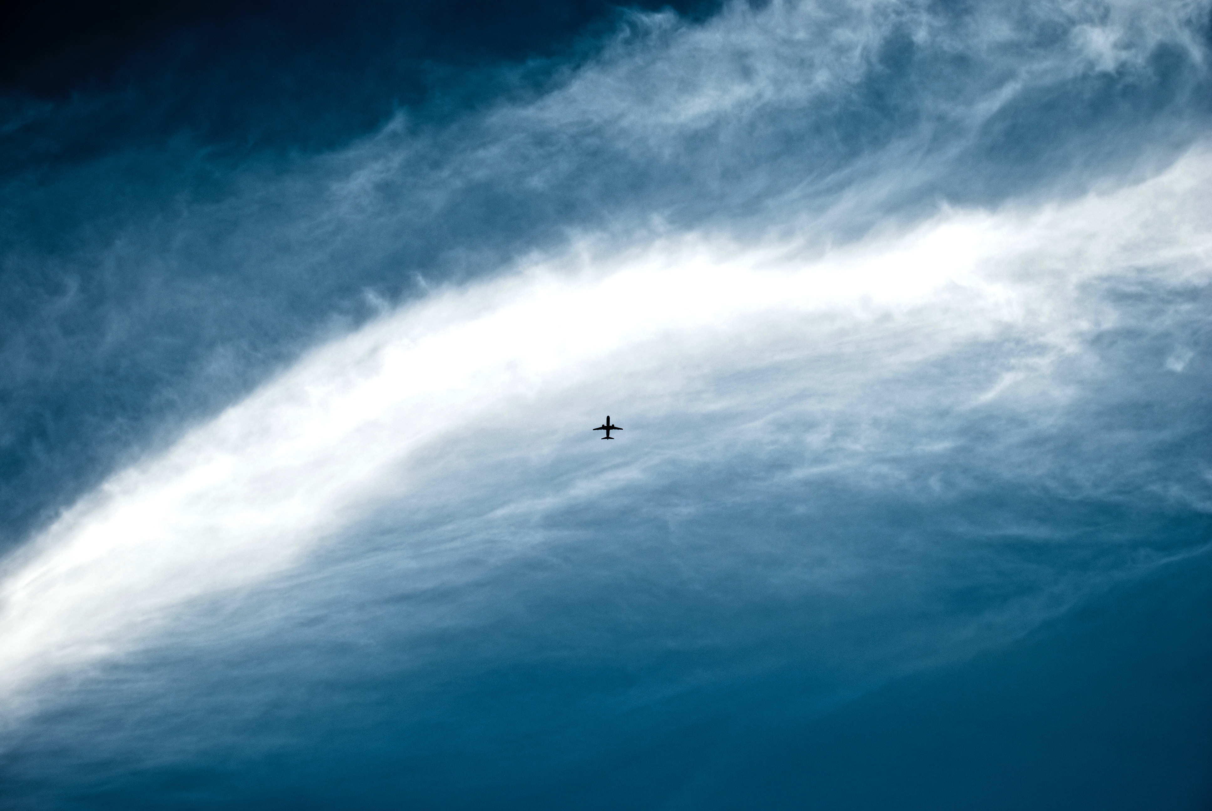 Airplane flying through a cloudy blue sky HD Wallpaper