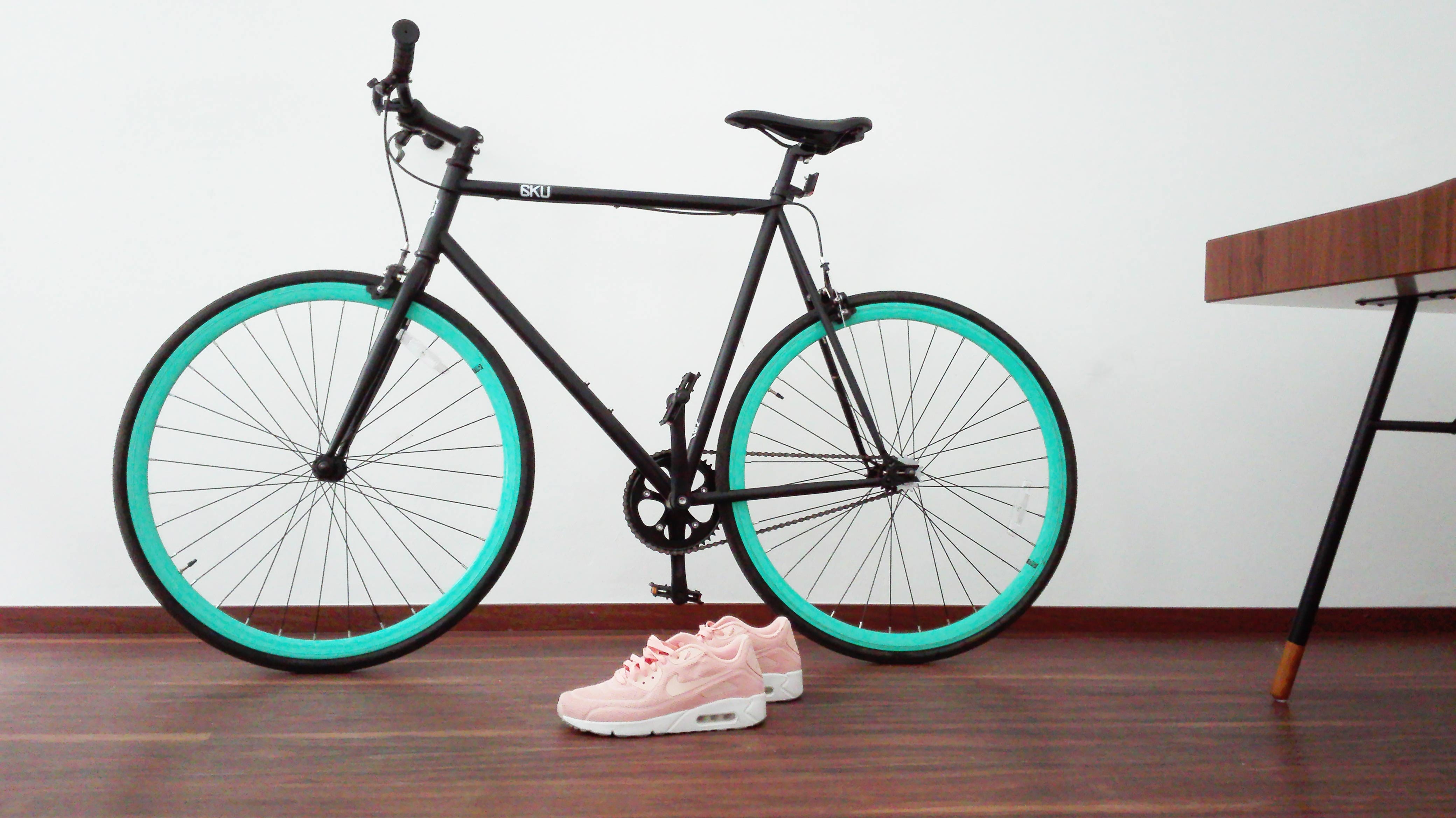 Black fixed wheel bicycle with teal rims and pink sneakers HD Wallpaper