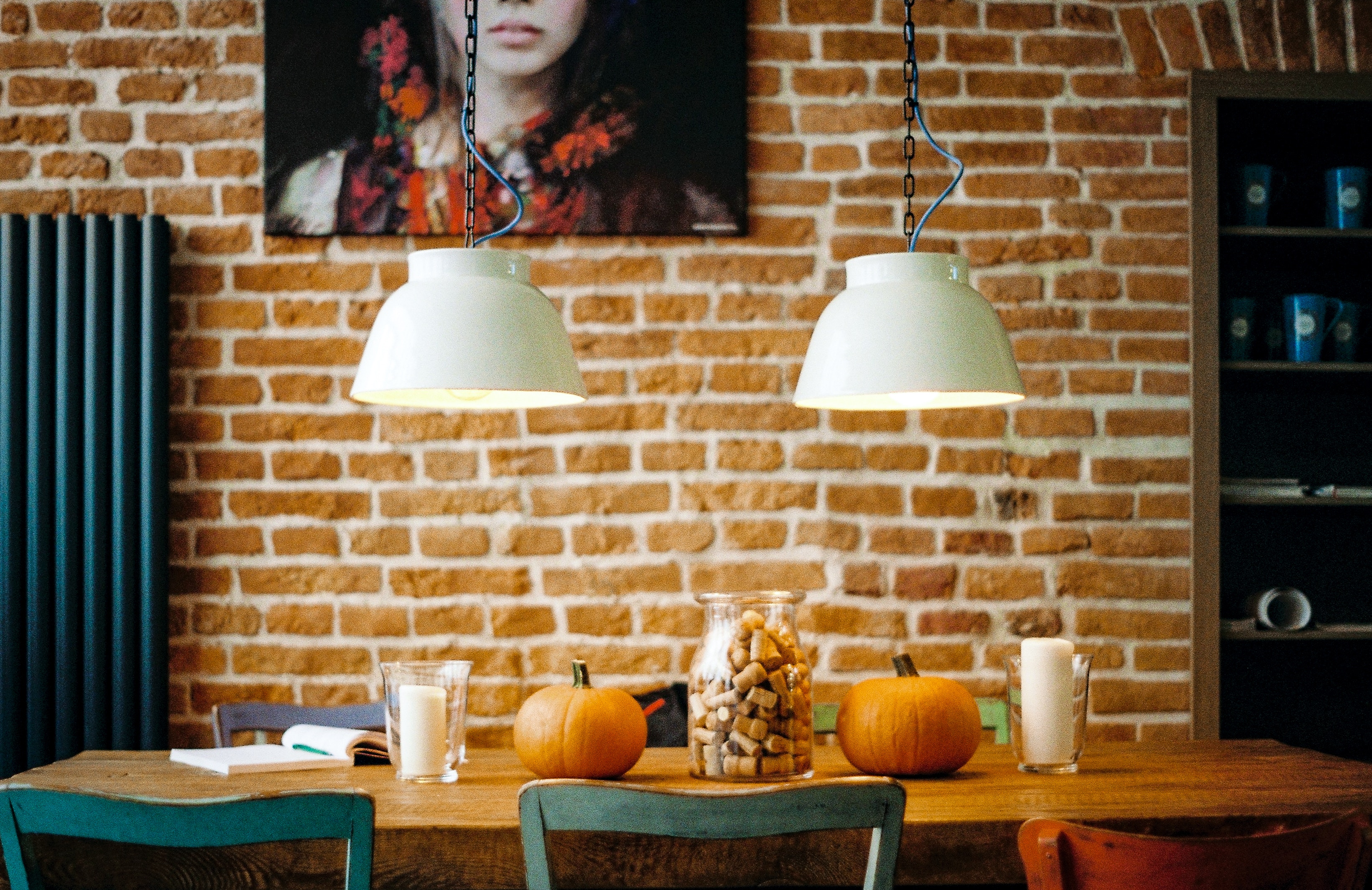 Two pendant lights over a brick wall with pumpkins on a table HD Wallpaper
