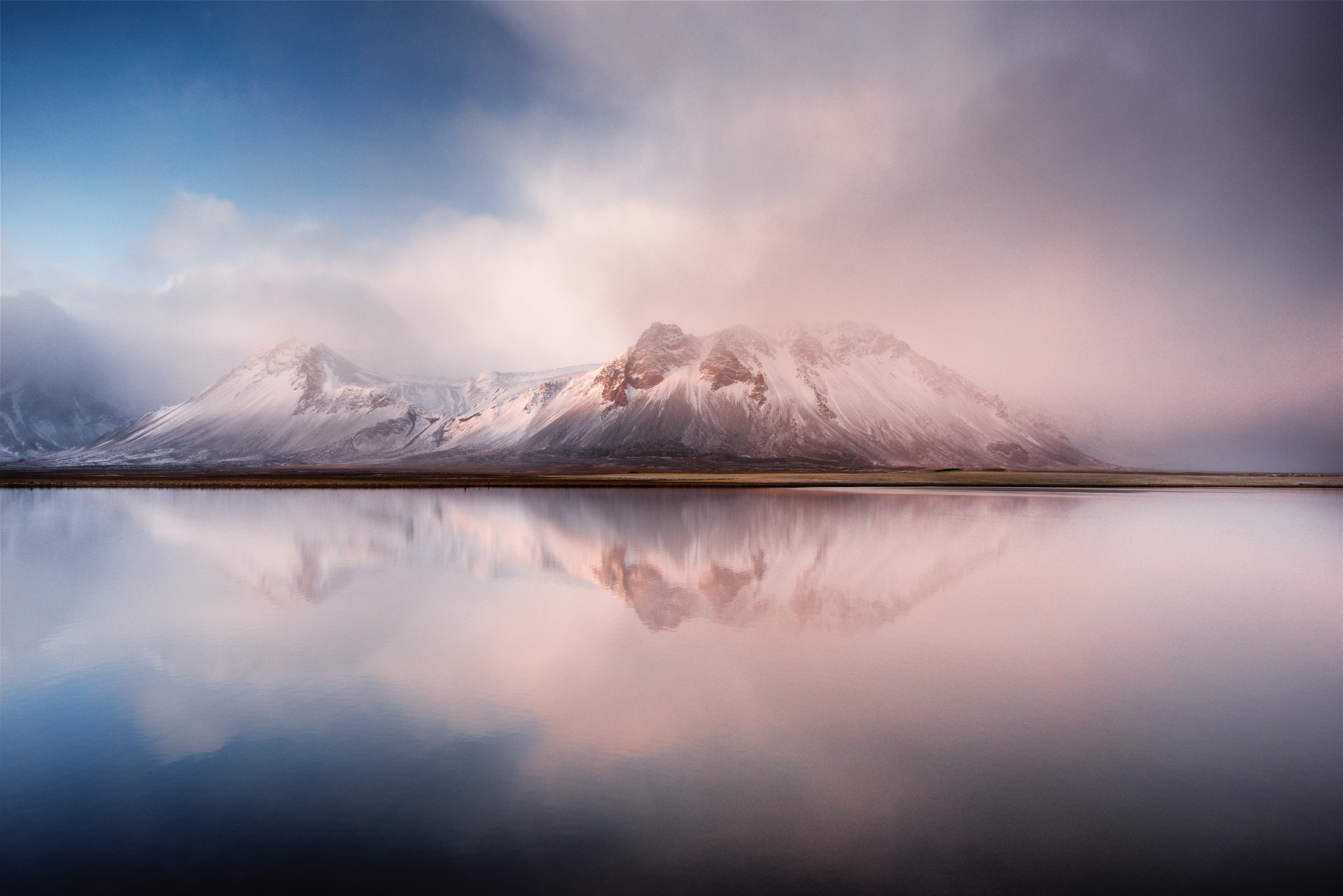 Snow-capped mountains reflected in a calm lake in Iceland HD Wallpaper
