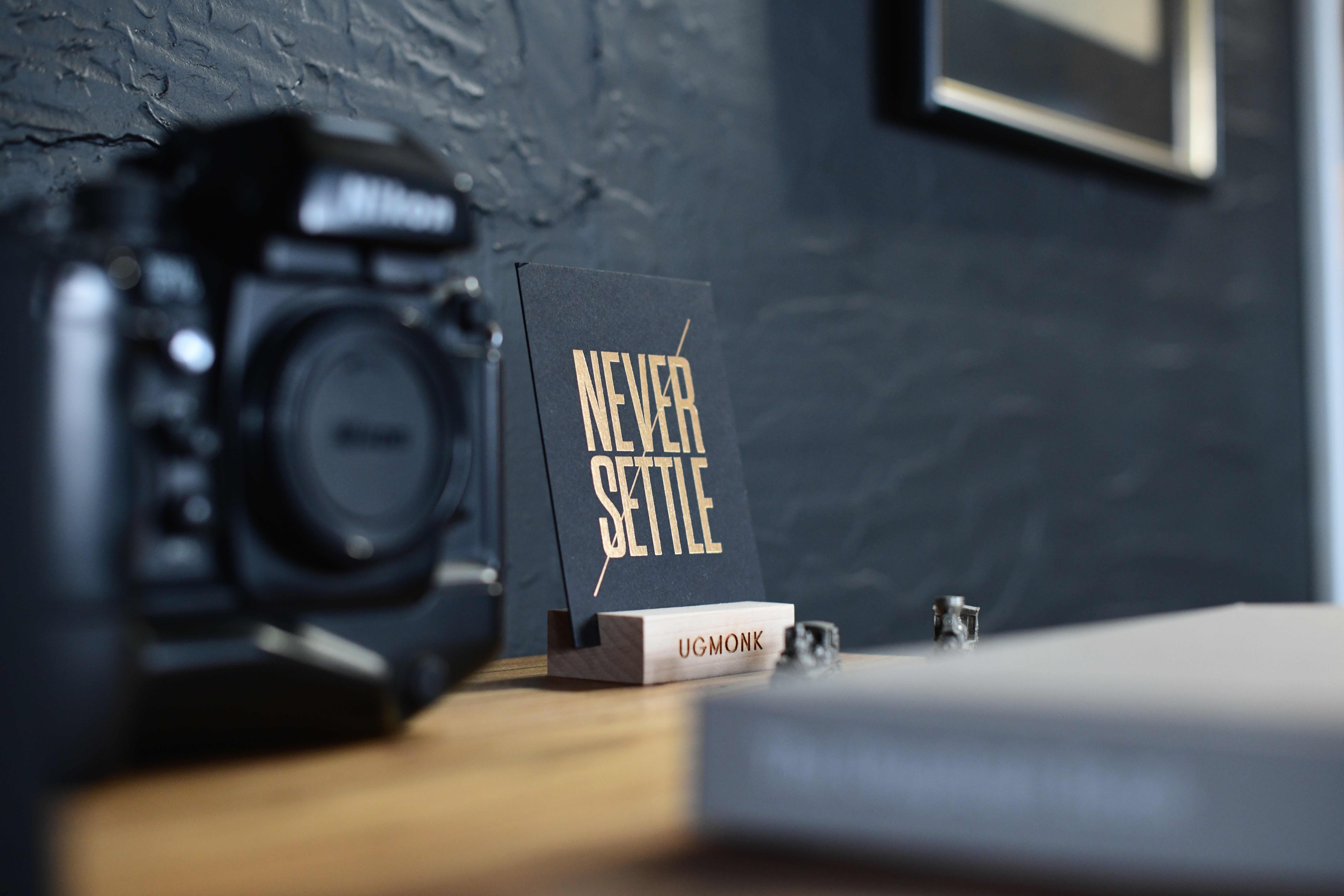 Nikon camera and "Never Settle" quote on a desk HD Wallpaper