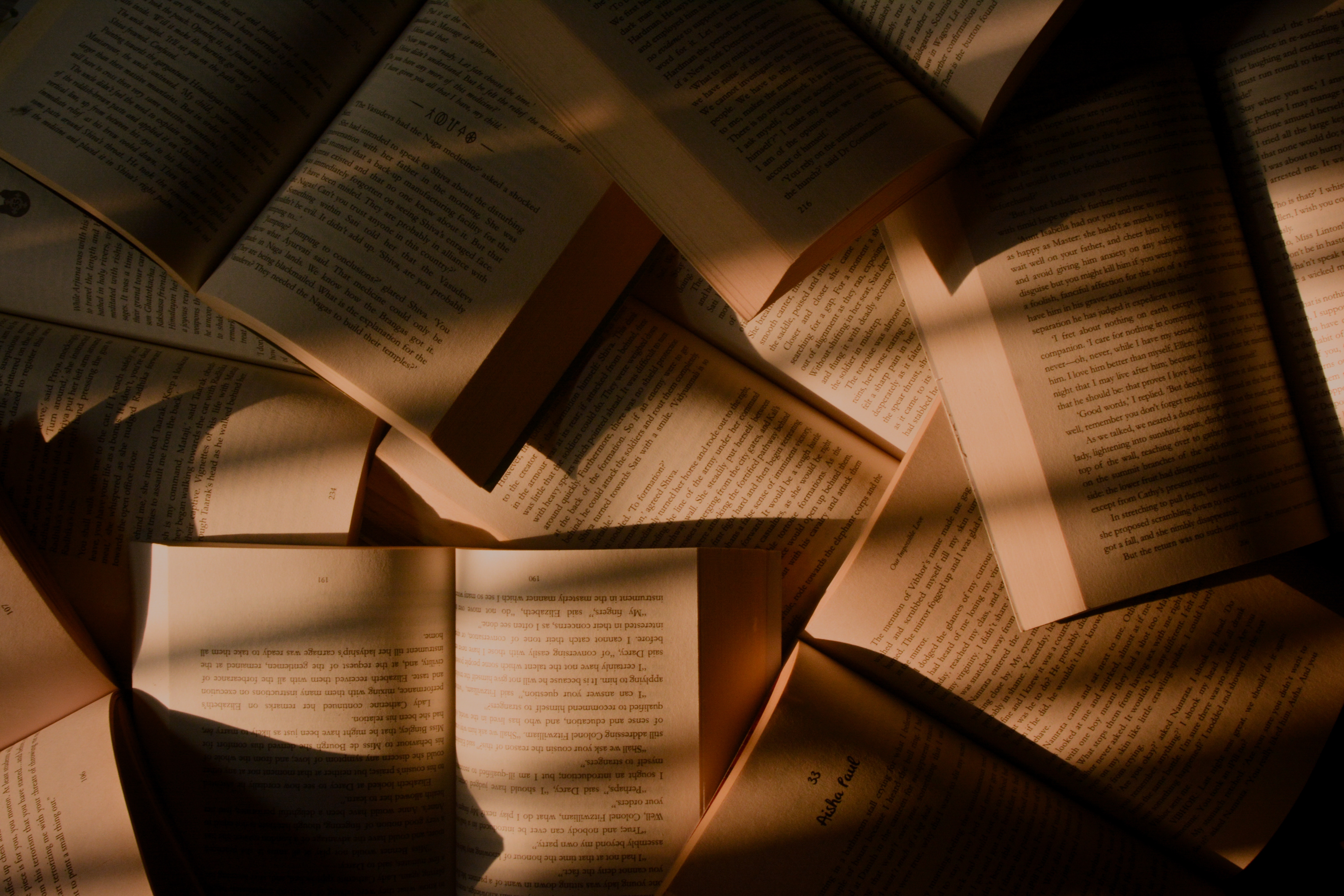 Scattered open books with sunlight and shadows HD Wallpaper