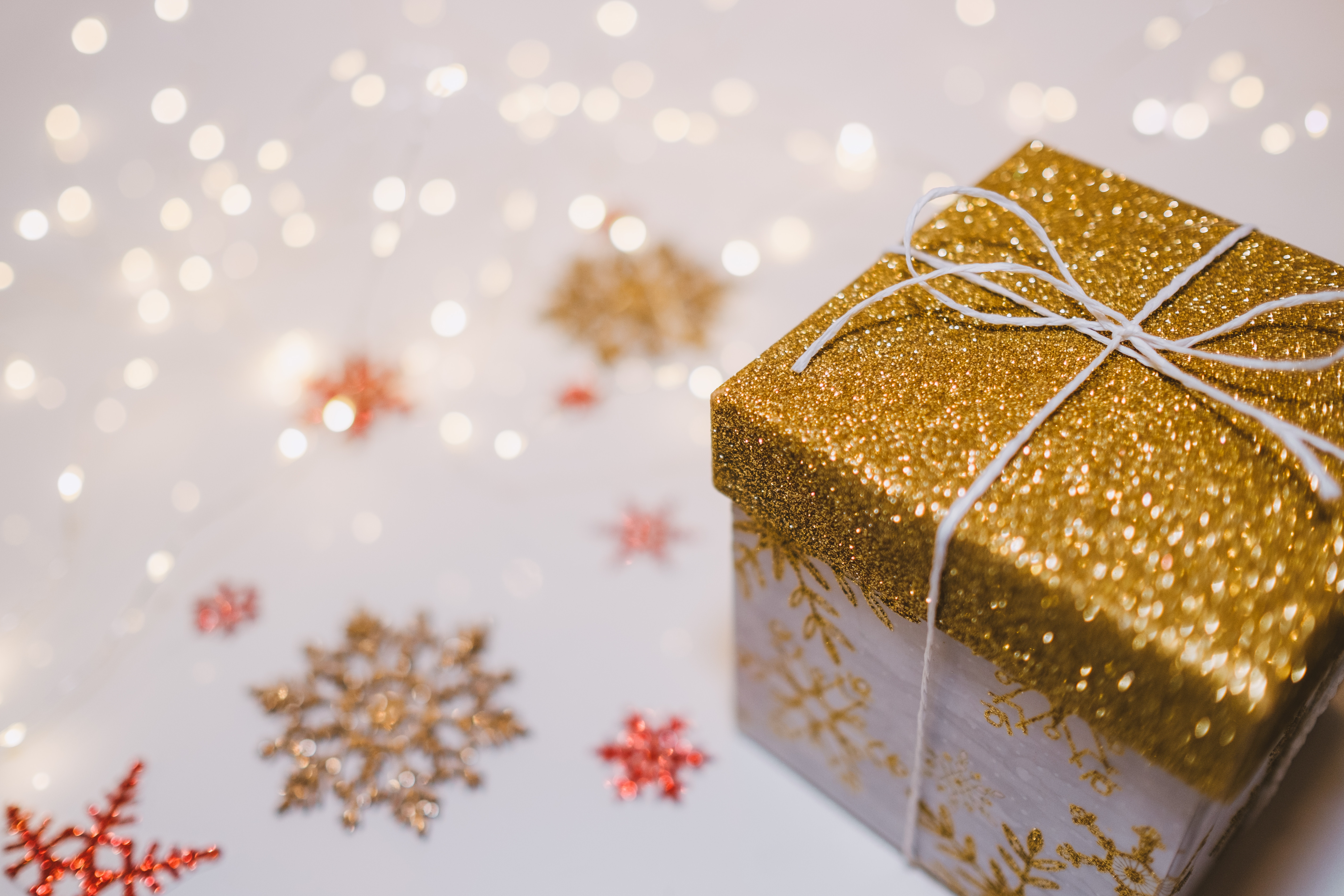 Gold glitter gift box with snowflakes and bokeh lights HD Wallpaper