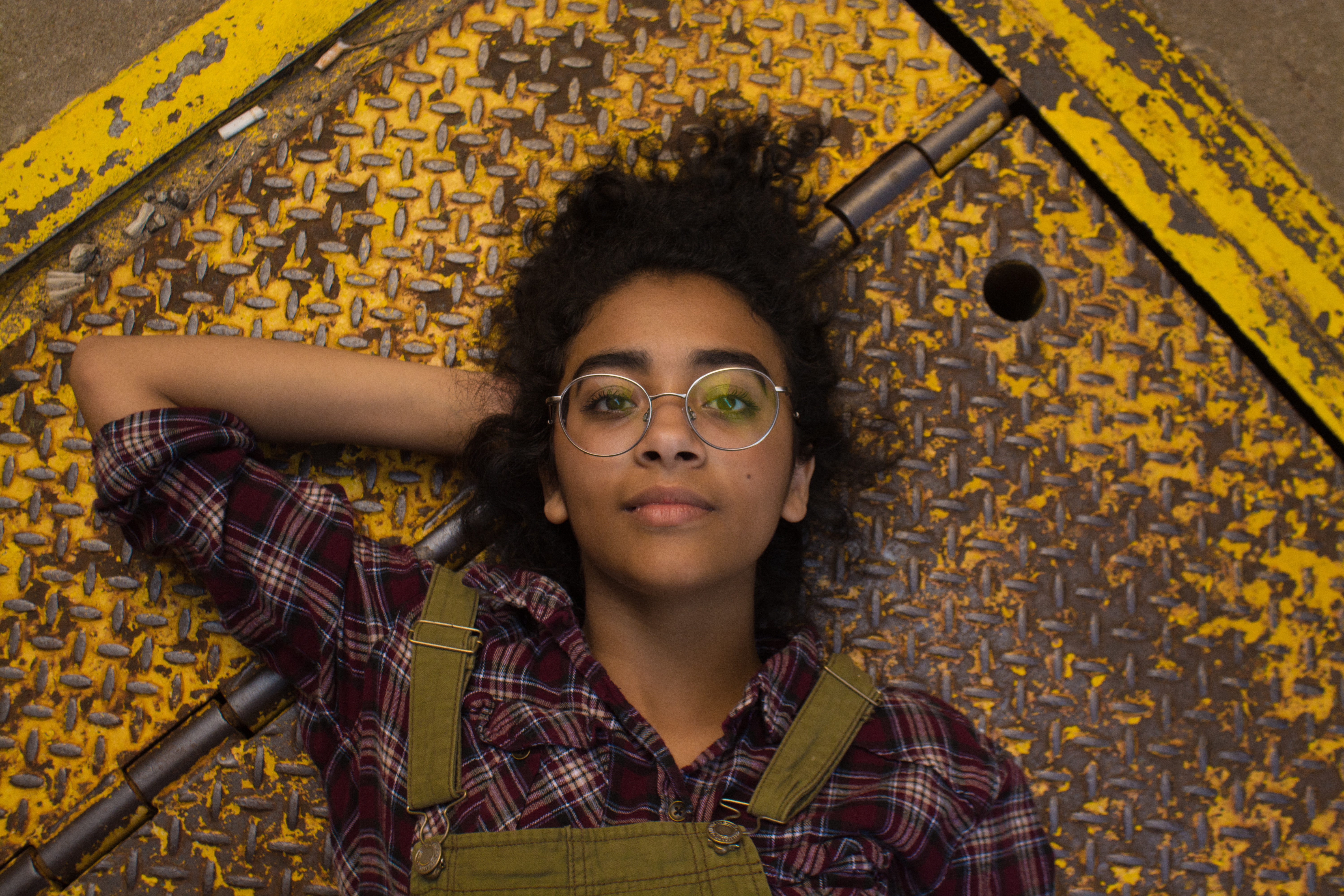 Young woman with glasses lying on metal surface HD Wallpaper