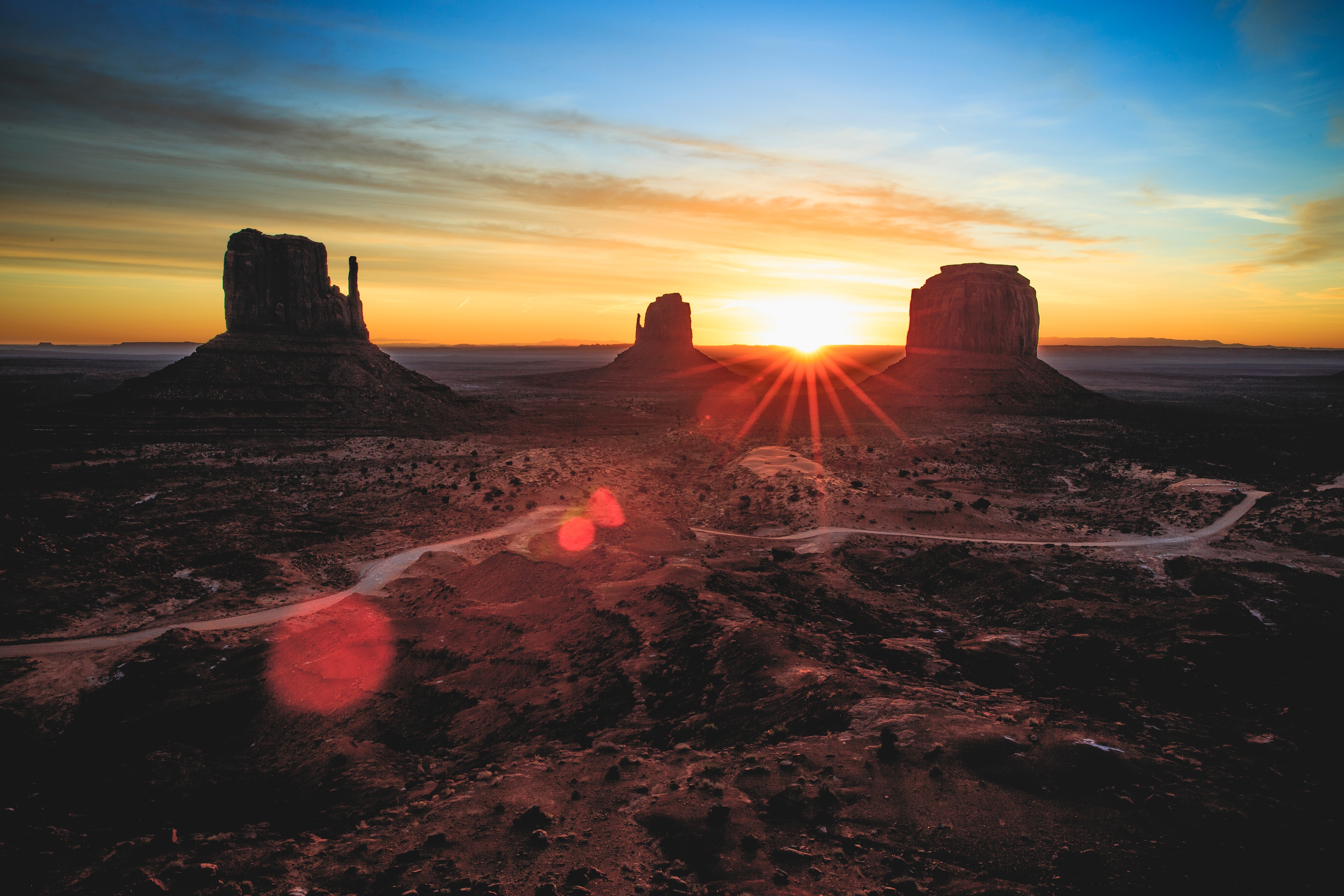 Monument Valley sunrise with sun flares and road HD Wallpaper