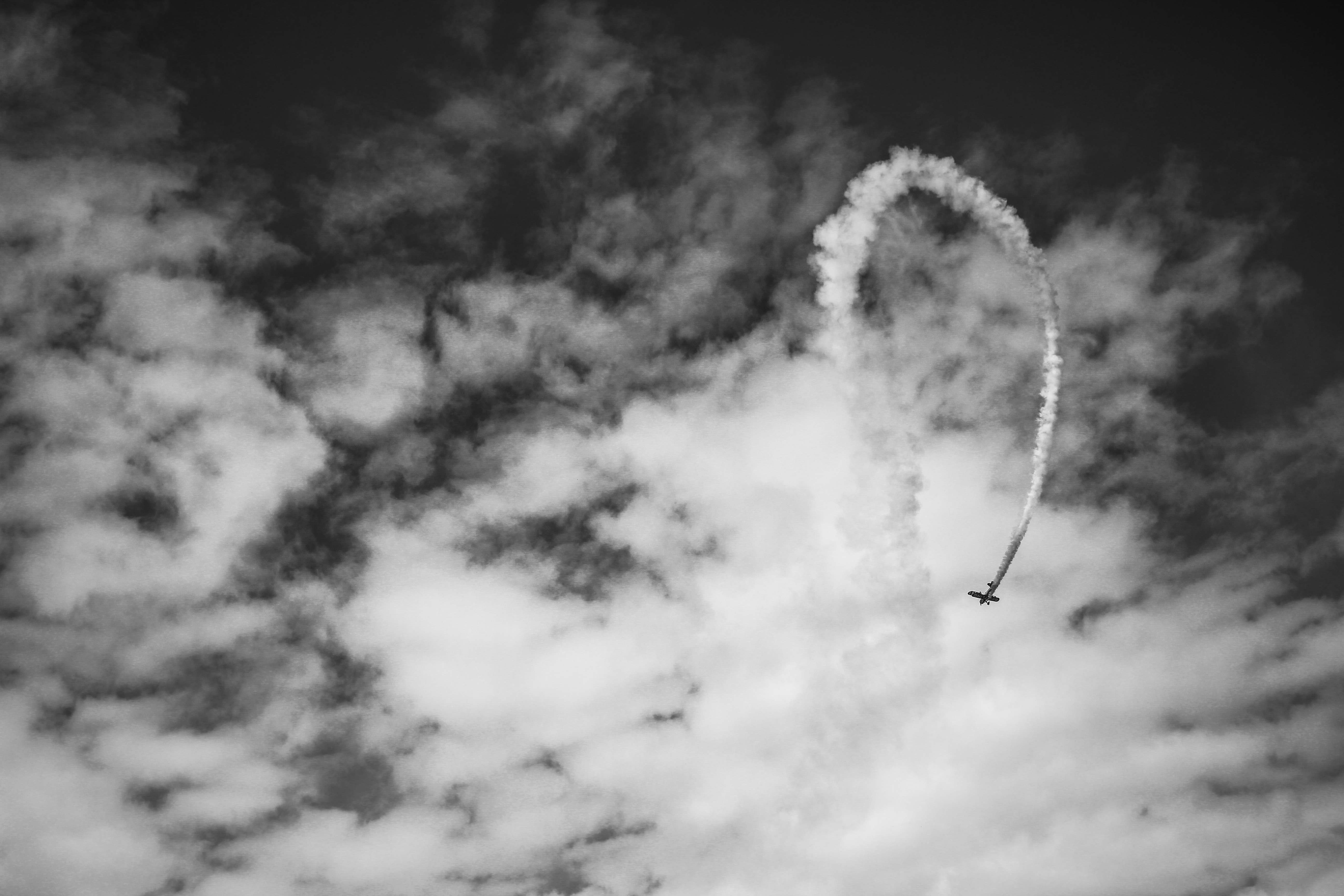 Airplane performing a loop with smoke trail in cloudy sky HD Wallpaper