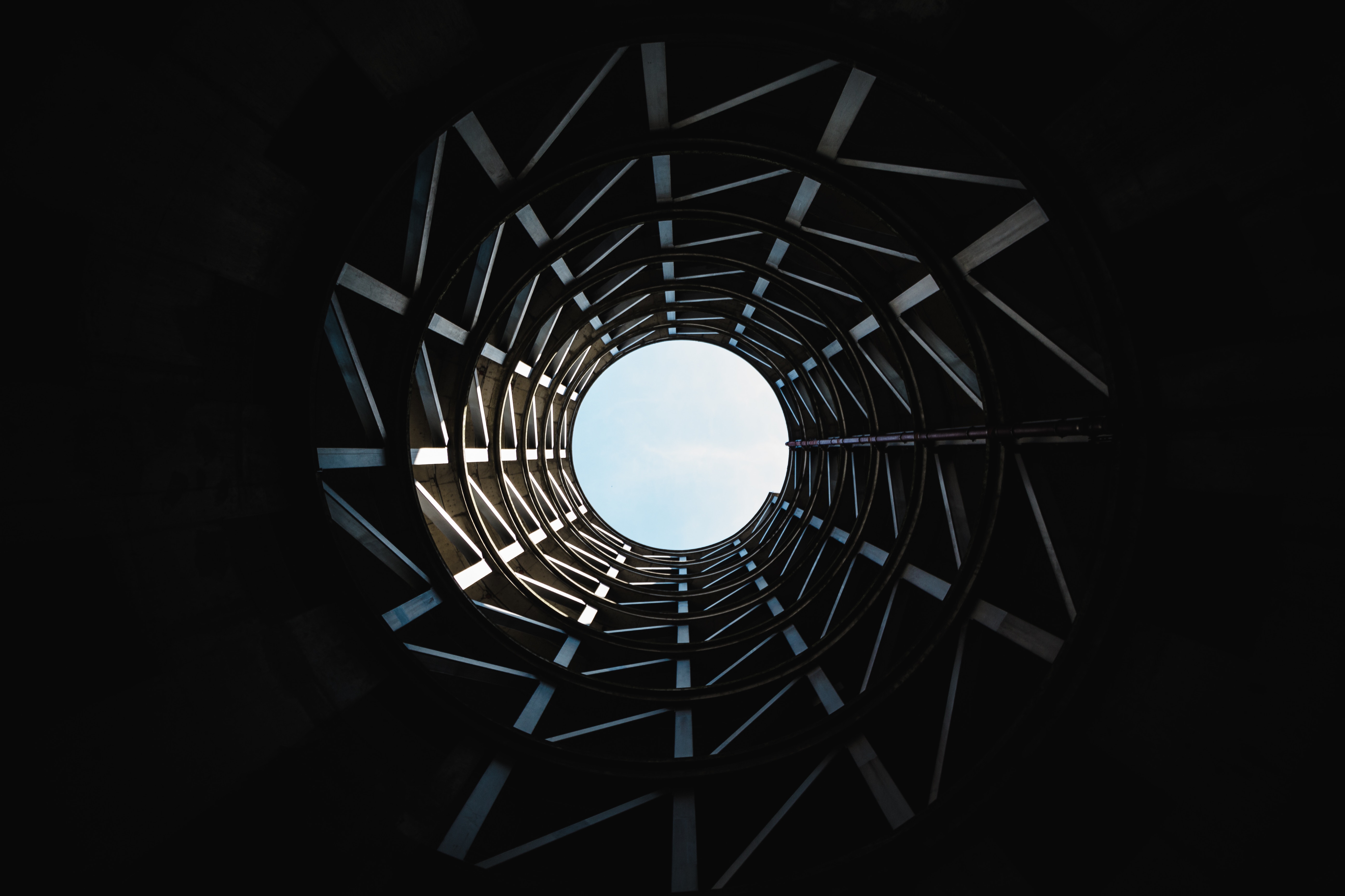 Looking up through a circular concrete structure towards the sky HD Wallpaper