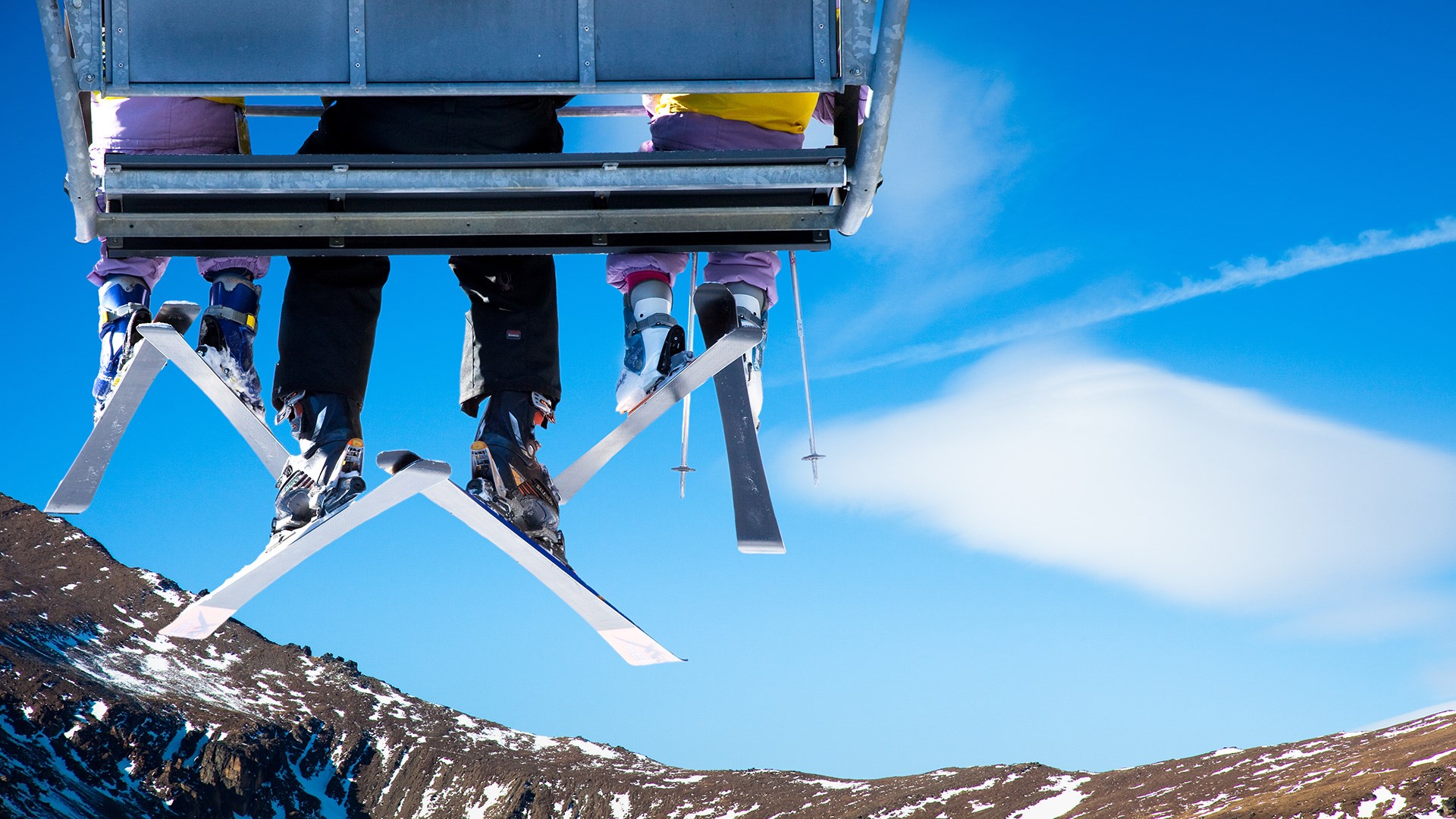 People on a ski lift with snowy mountains and blue sky HD Wallpaper