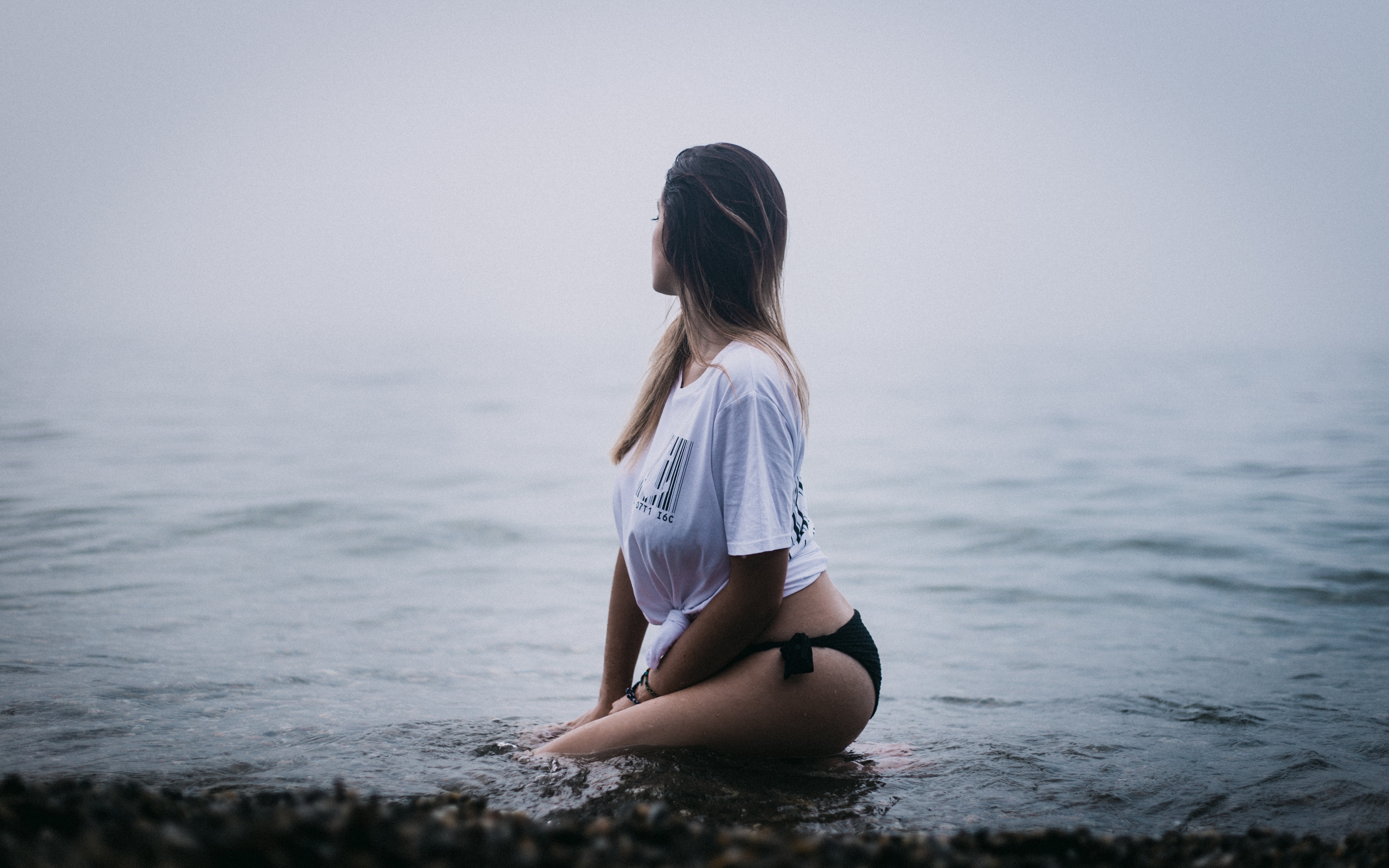 Young Woman Sitting in Calm Water at Beach HD Wallpaper