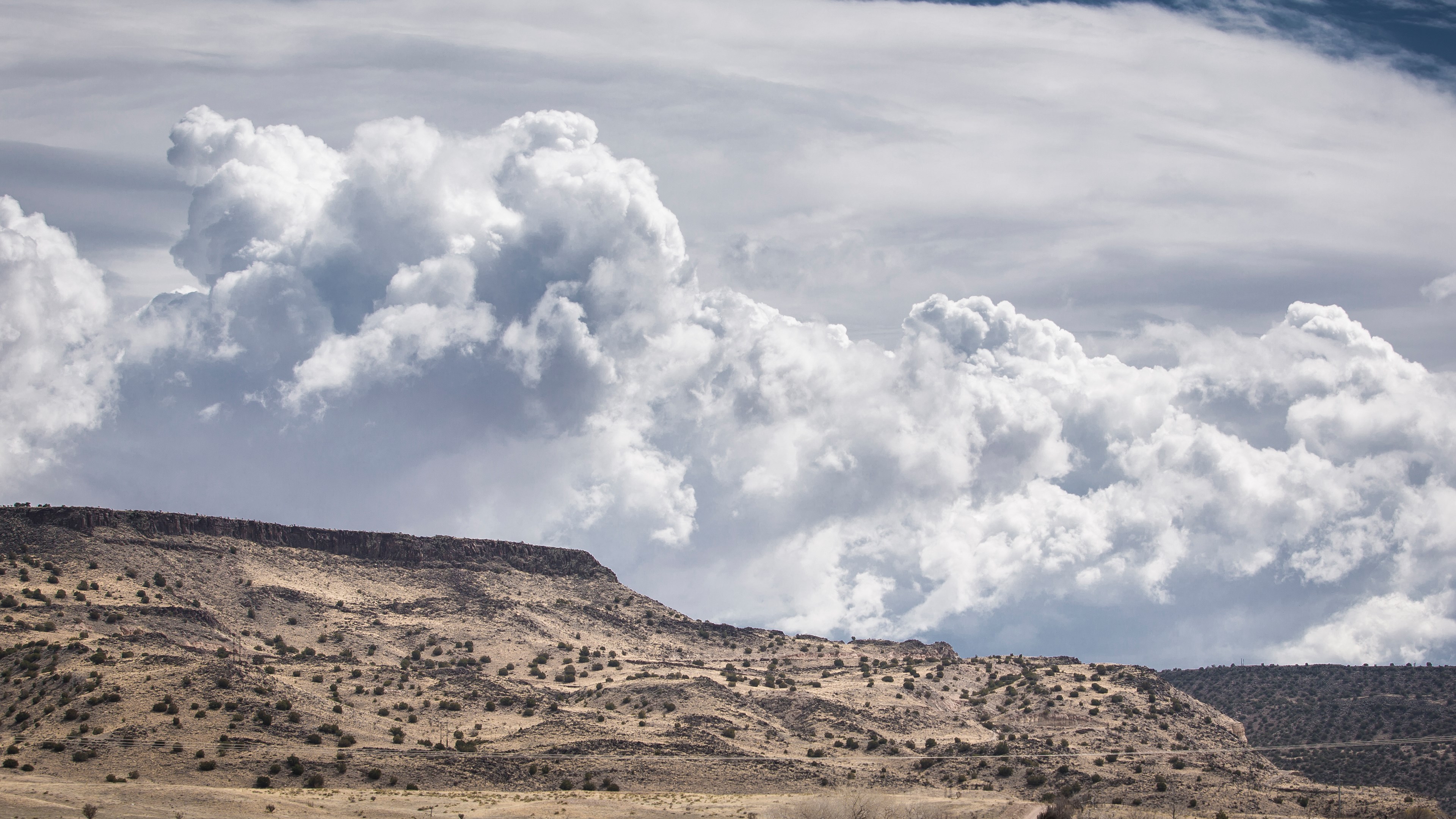 Cumulonimbus clouds over a desert mountain range HD Wallpaper