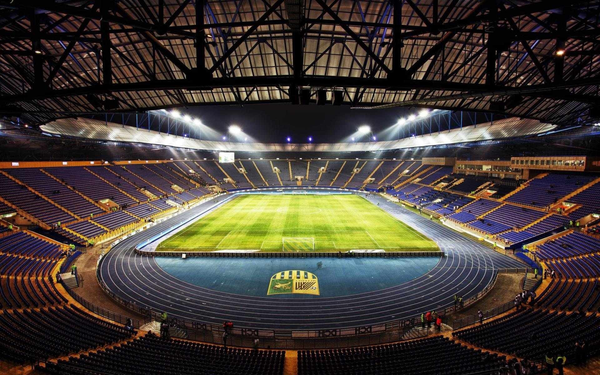 Soccer stadium with blue seats and green field HD Wallpaper