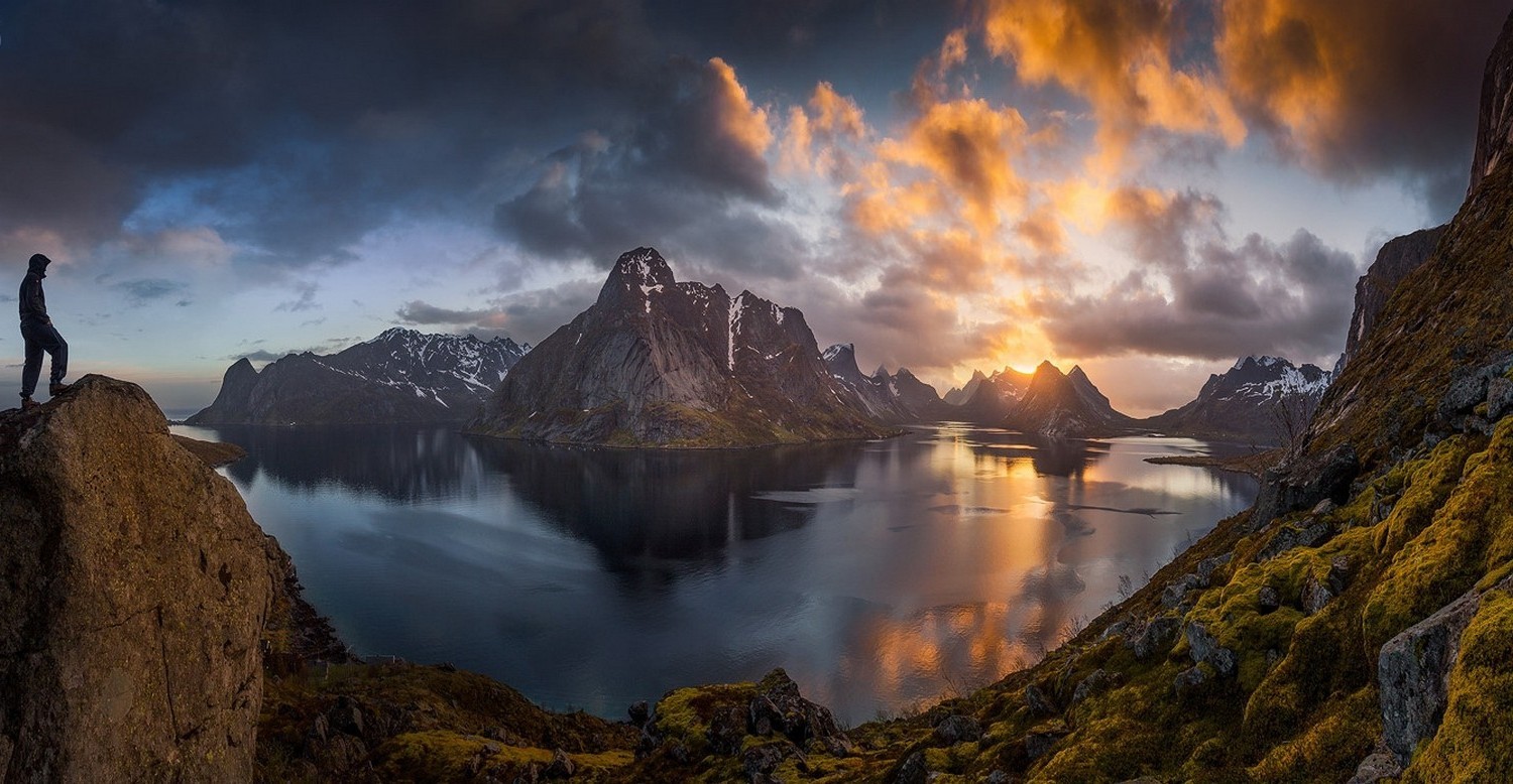 Man on cliff overlooking Lofoten Islands at sunset HD Wallpaper