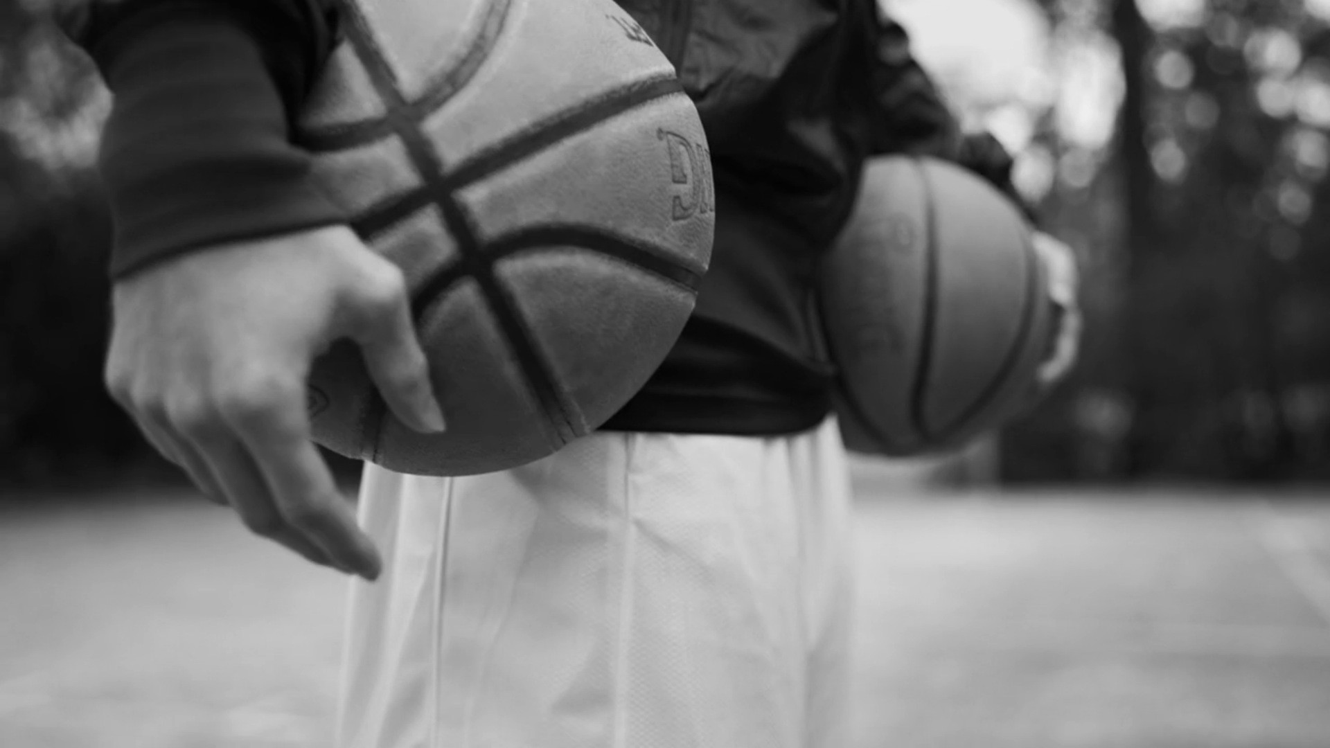 Person holding two basketballs on a court HD Wallpaper