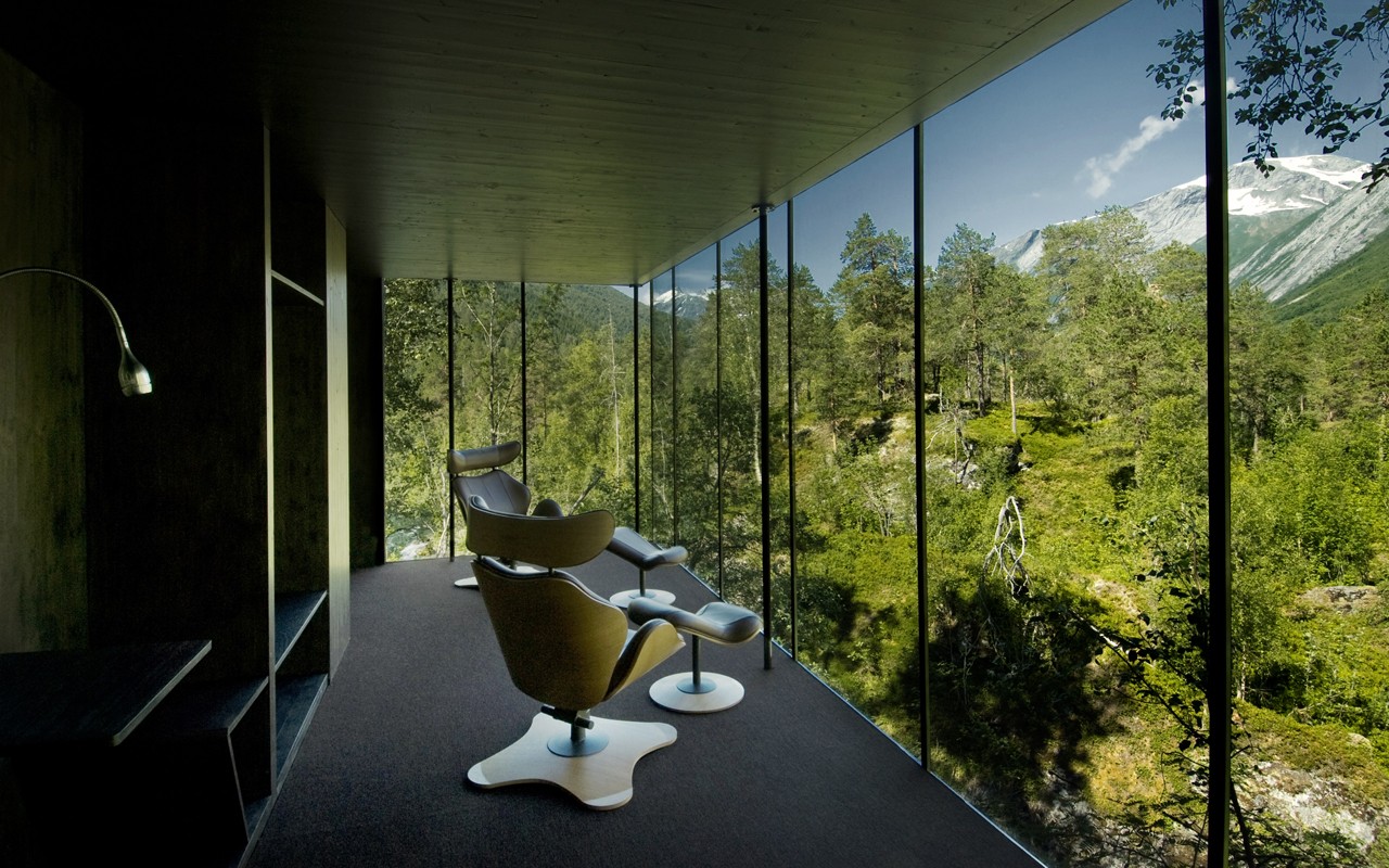 Modern hotel room with chairs overlooking a forest and mountains HD Wallpaper