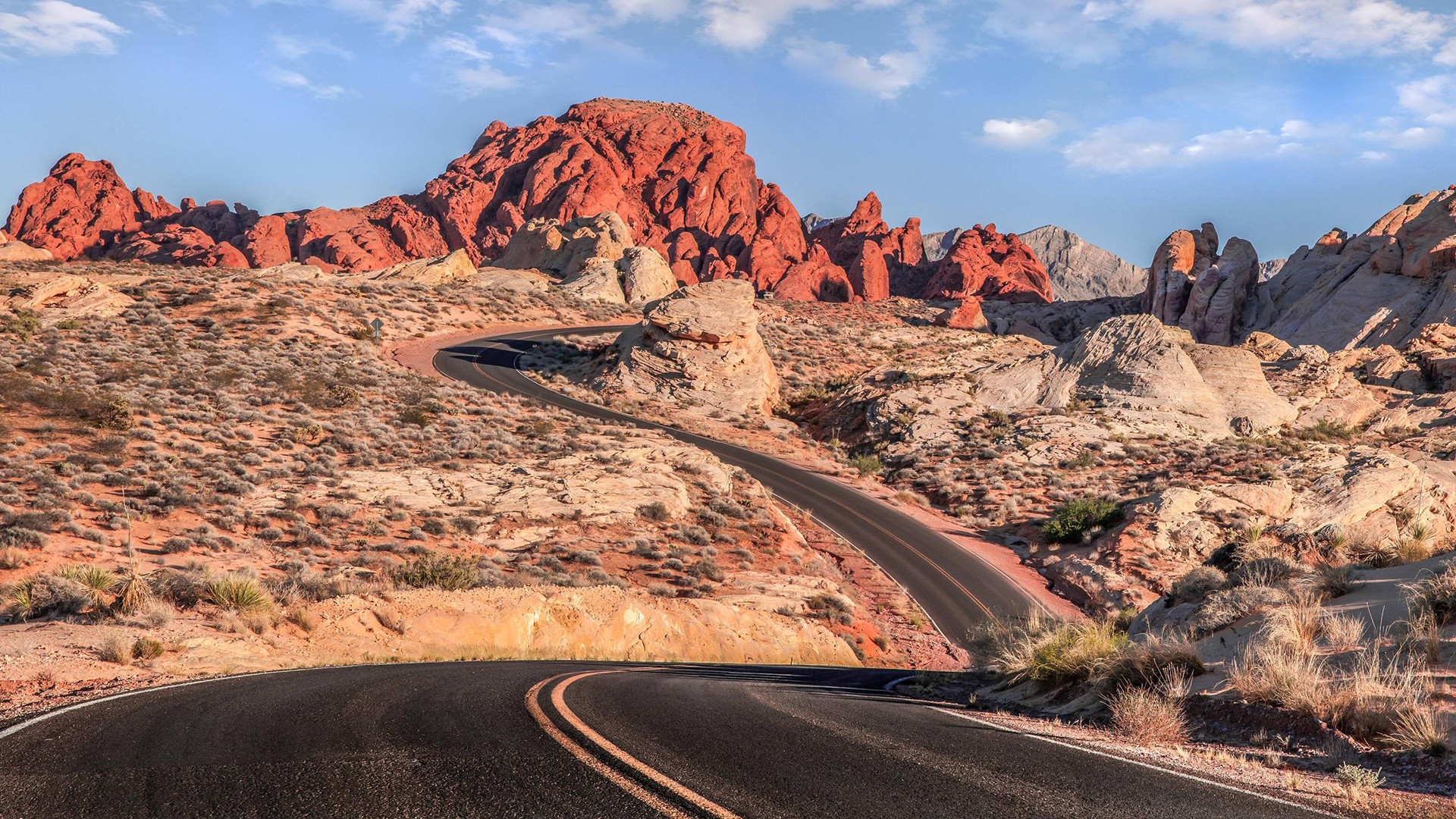 Scenic desert road winding through red rock formations HD Wallpaper