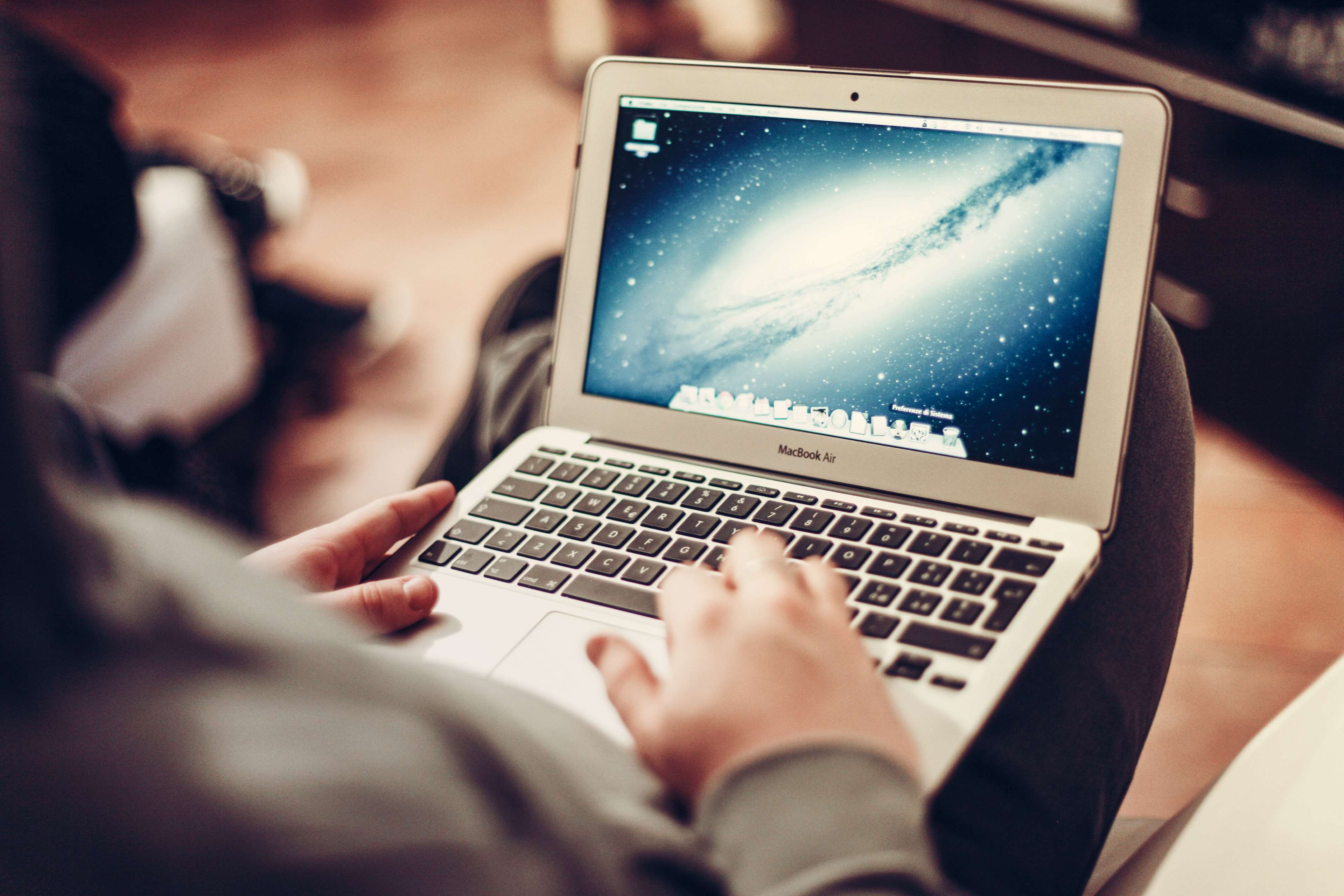 Person typing on a MacBook Air laptop with a galaxy wallpaper HD Wallpaper