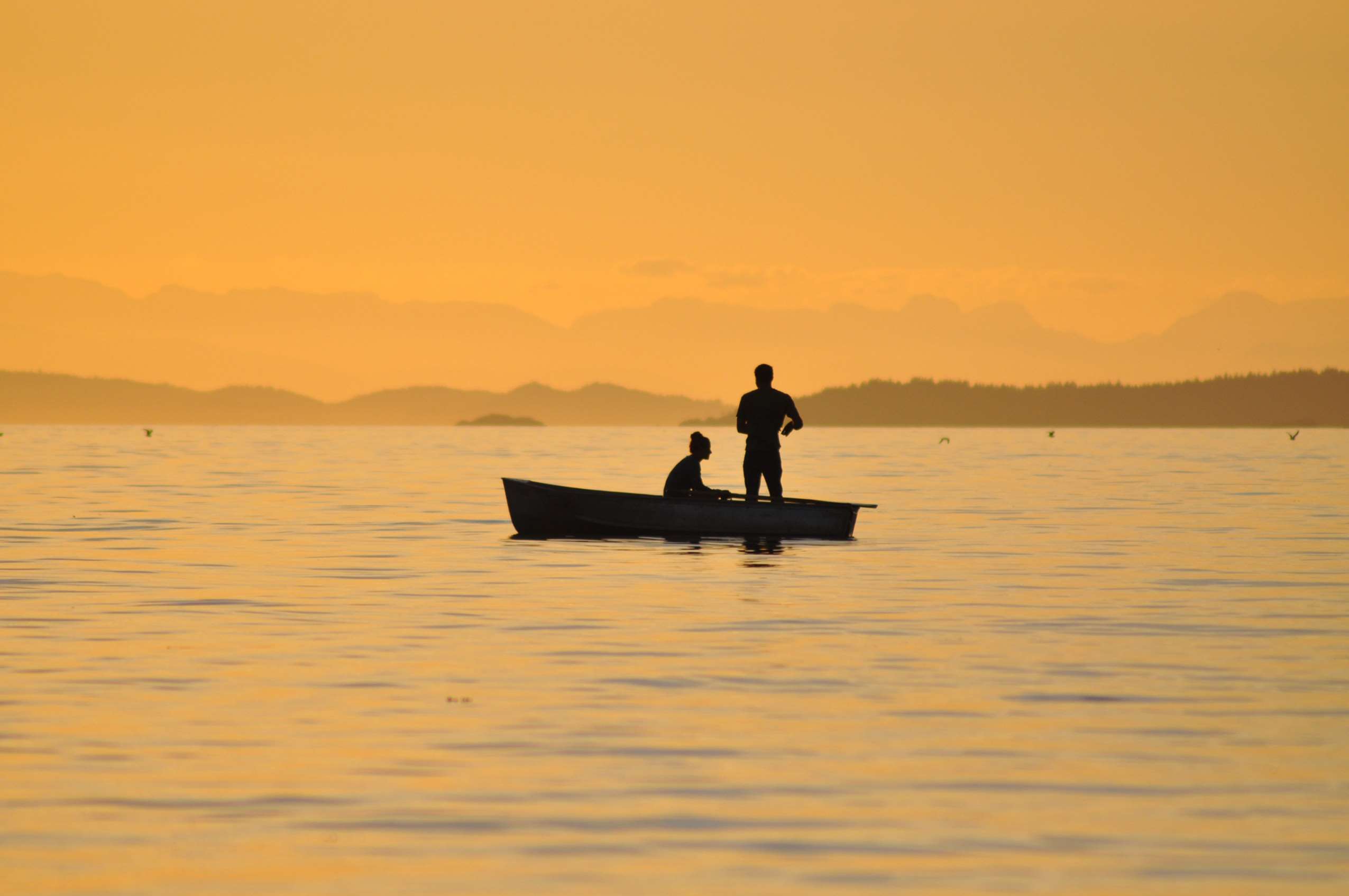 Two people in a boat at sunset HD Wallpaper