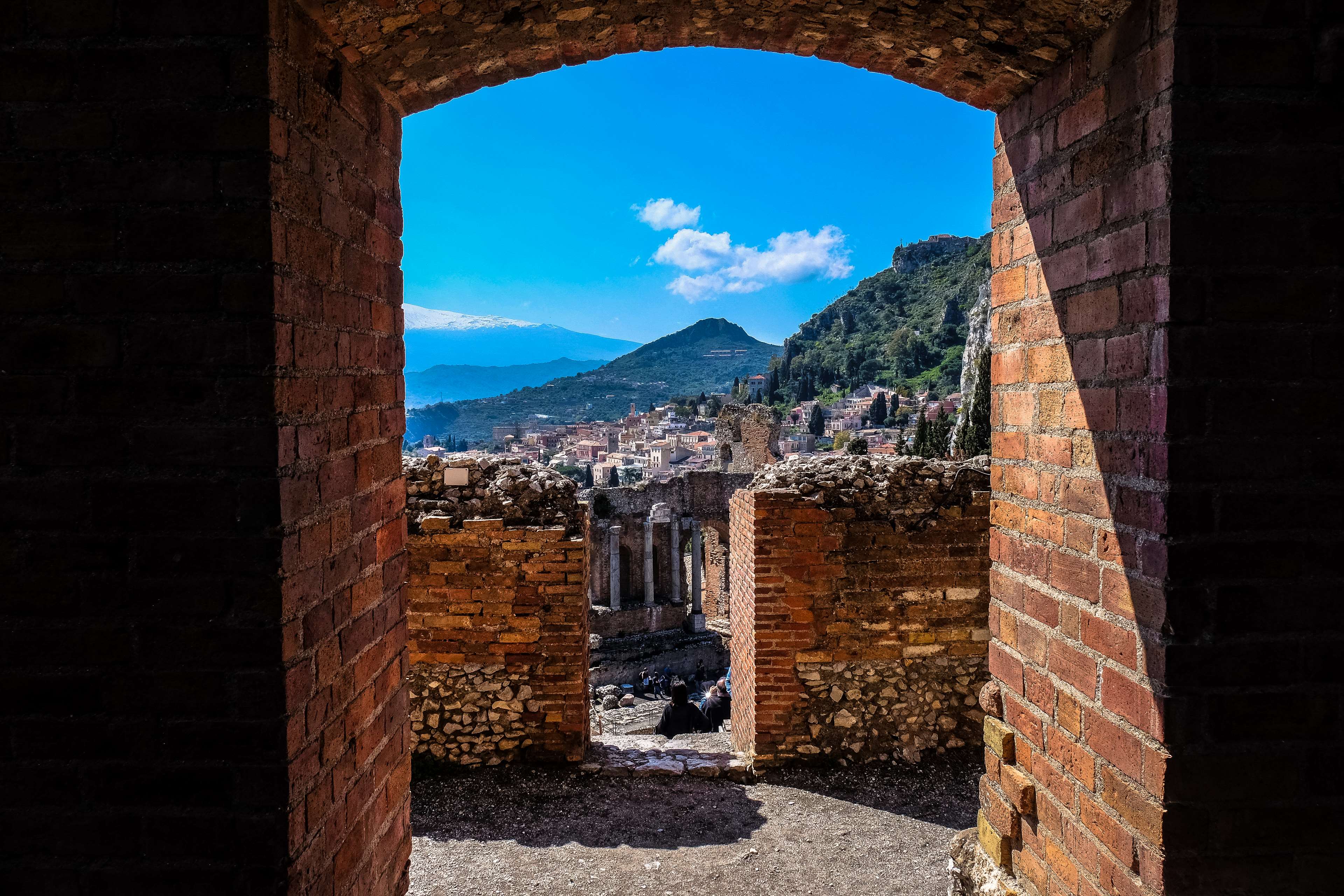 Ancient ruins with a town and mountains in the background HD Wallpaper