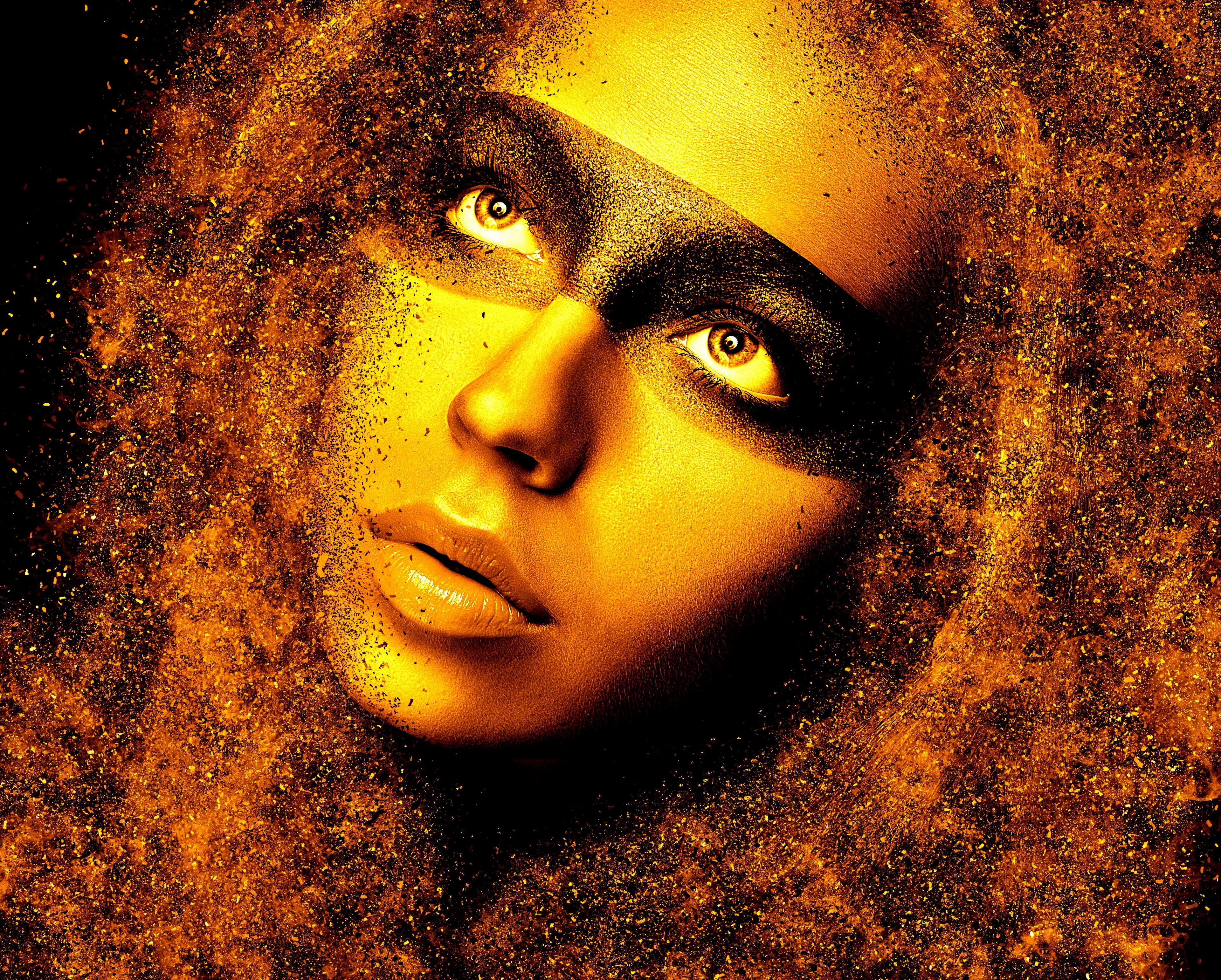 Woman's face with golden makeup and exploding particles HD Wallpaper