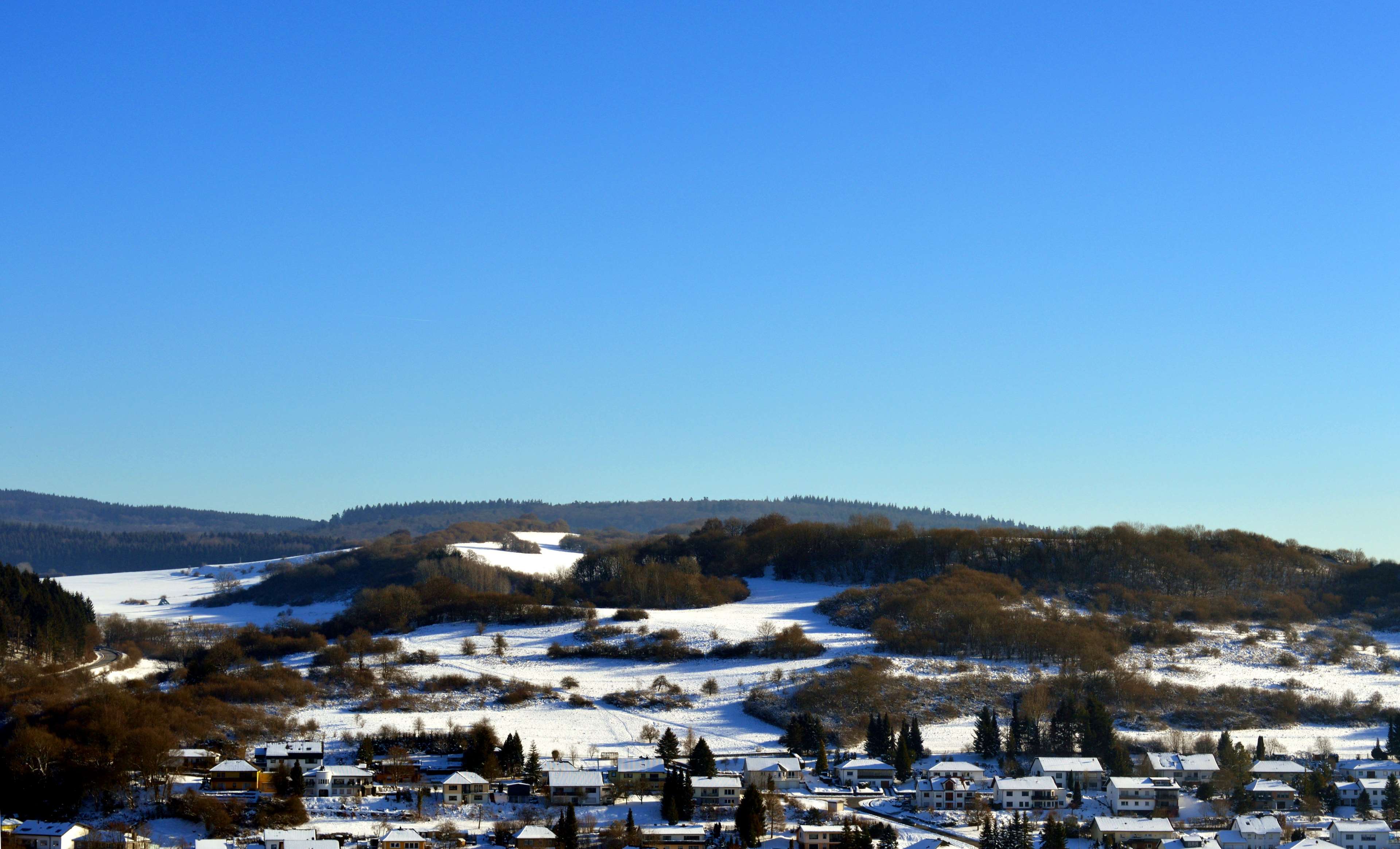 Winter landscape with snow-covered hills and houses in Eifel, Germany HD Wallpaper
