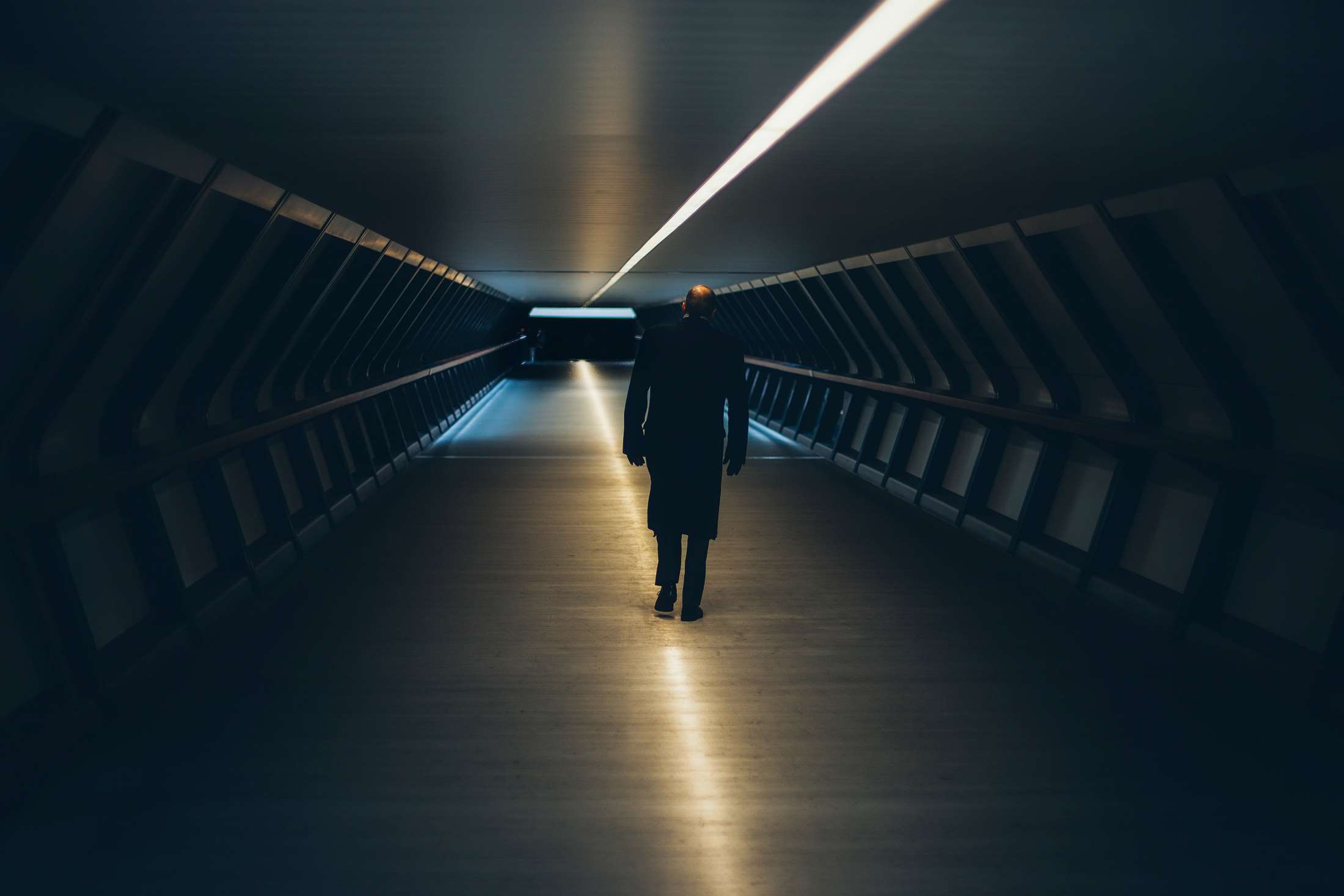 Man walking through a futuristic illuminated tunnel HD Wallpaper