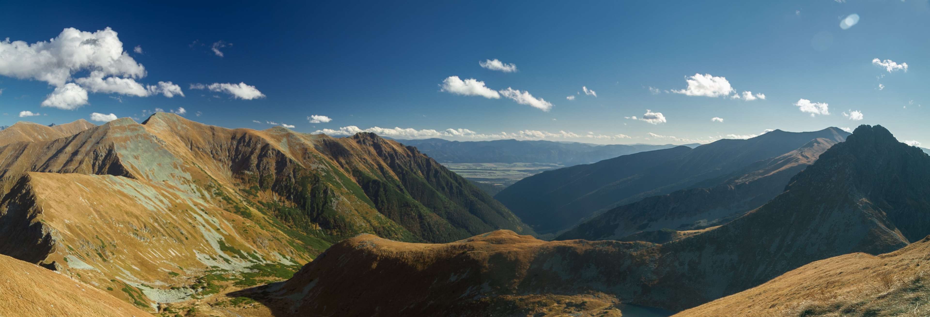 Panoramic view of mountains in autumn under a blue sky with clouds HD Wallpaper