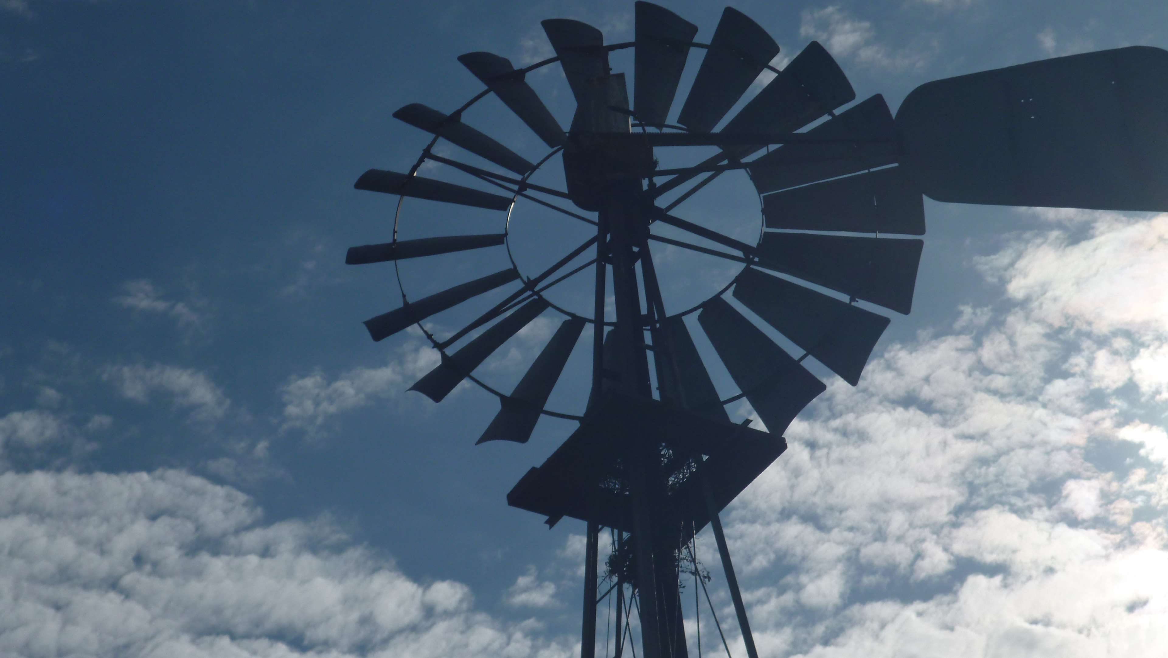 Silhouette of an old windmill against a blue sky with clouds HD Wallpaper