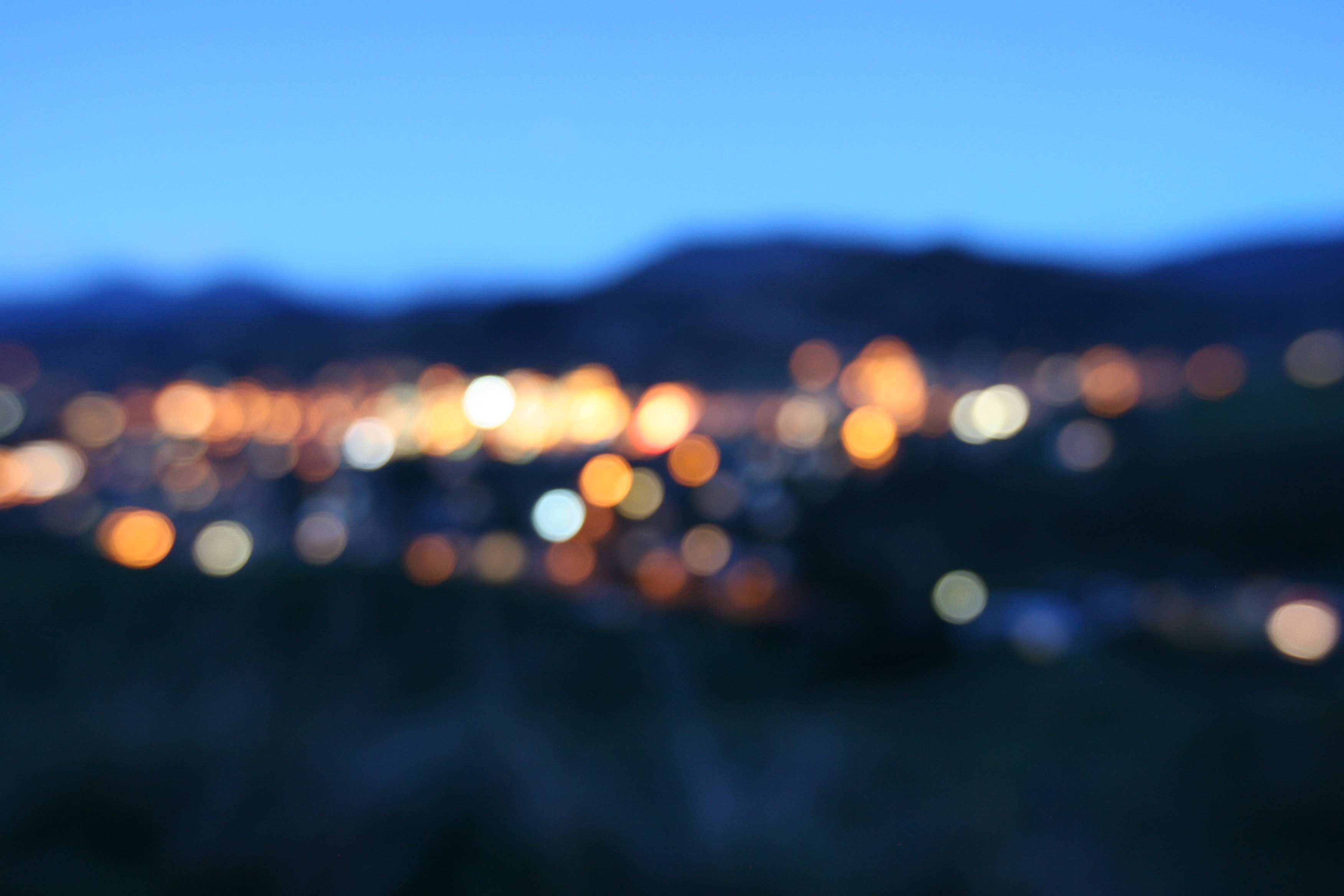 Blurred city lights at night with mountains HD Wallpaper