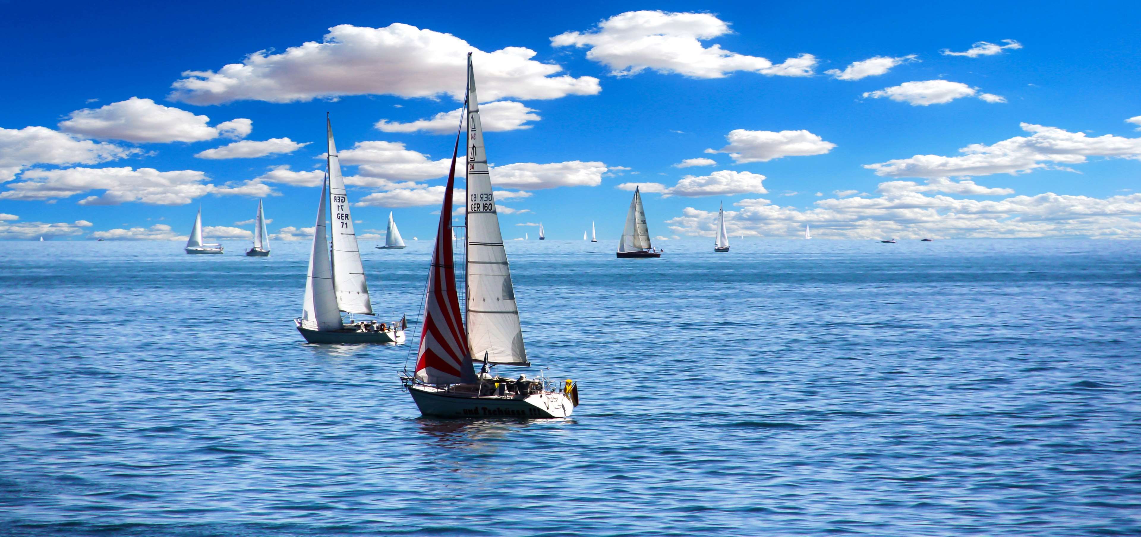 Sailboats on the ocean under a cloudy blue sky 4K HD Wallpaper