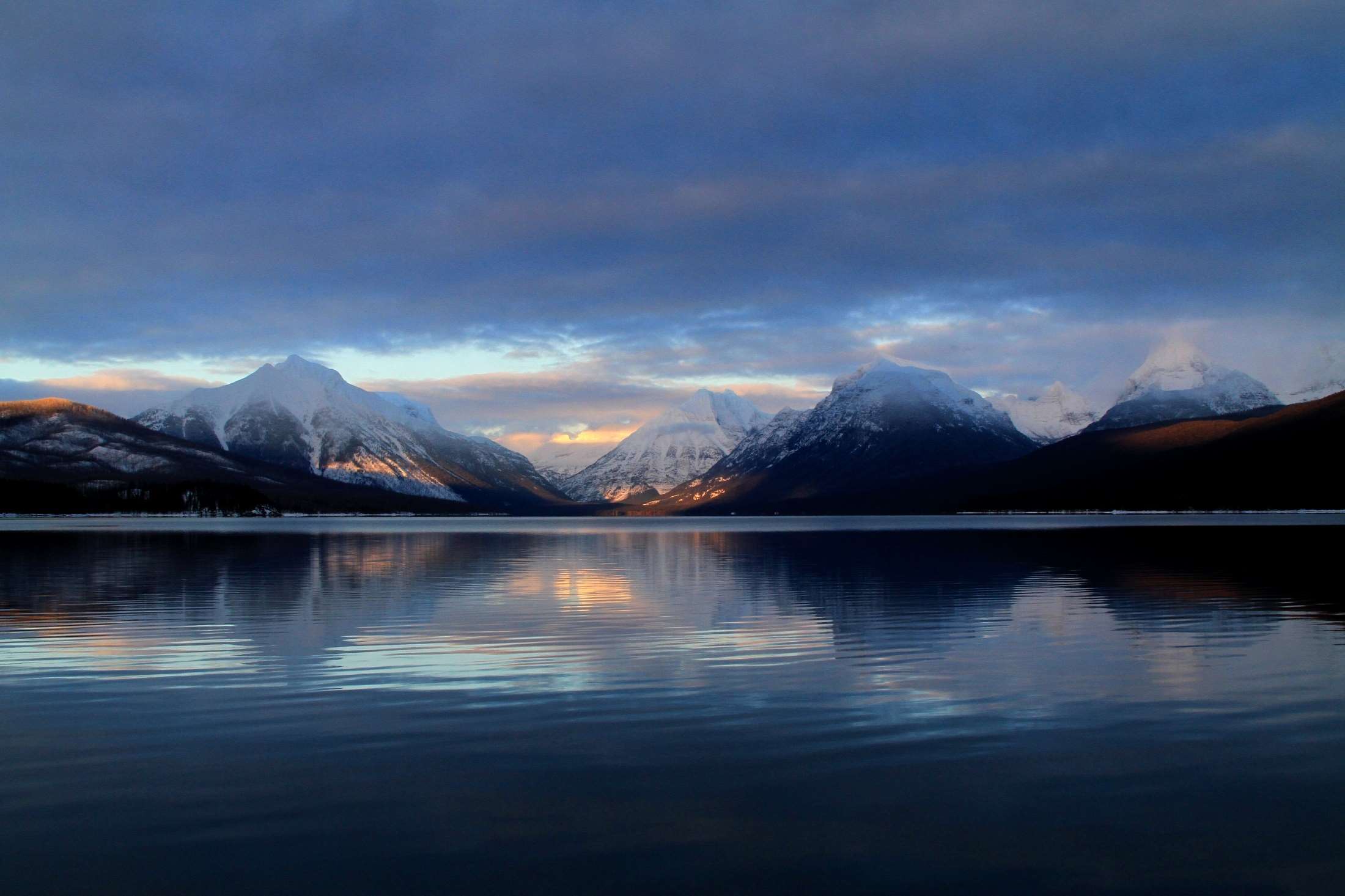 Snow-capped mountains reflected in a calm lake at dusk HD Wallpaper