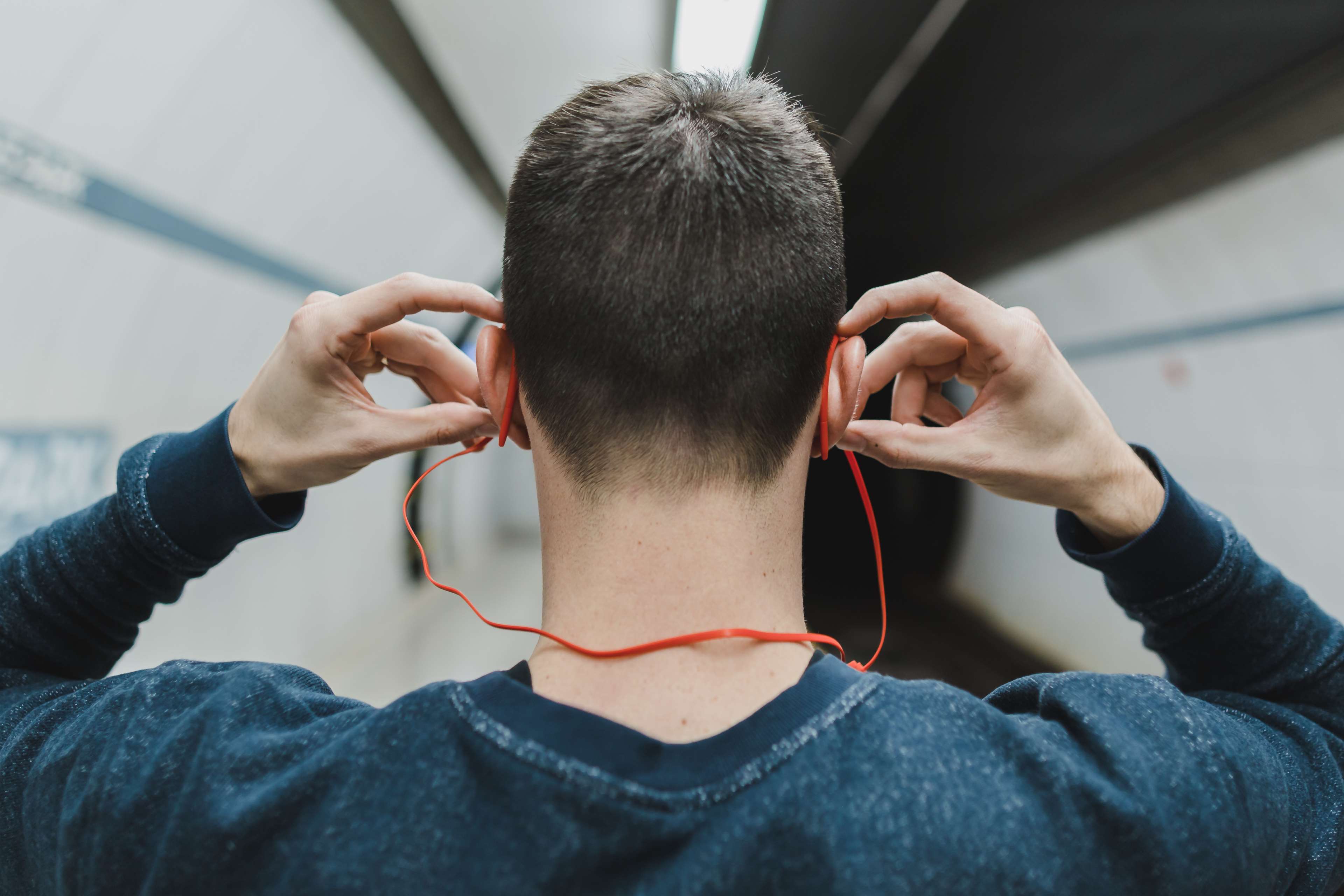 Man putting on red earphones in subway tunnel HD Wallpaper