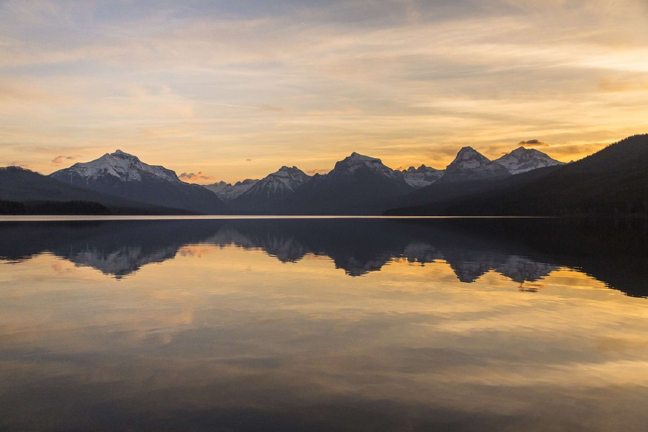 Sunrise over Lake McDonald with snow-capped mountains in Glacier National Park HD Wallpaper