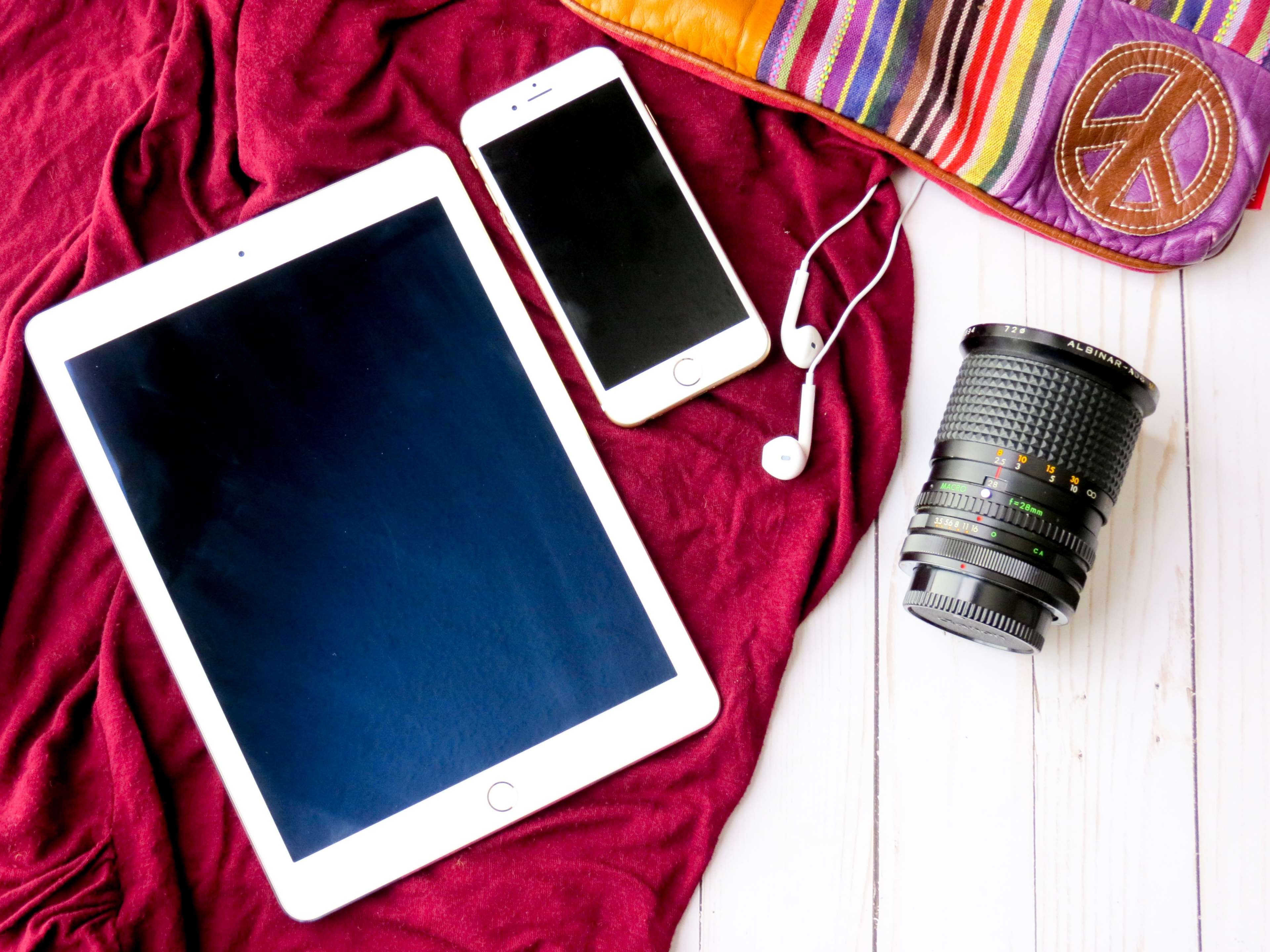 Flatlay of tablet, iPhone, headphones, and camera lens HD Wallpaper