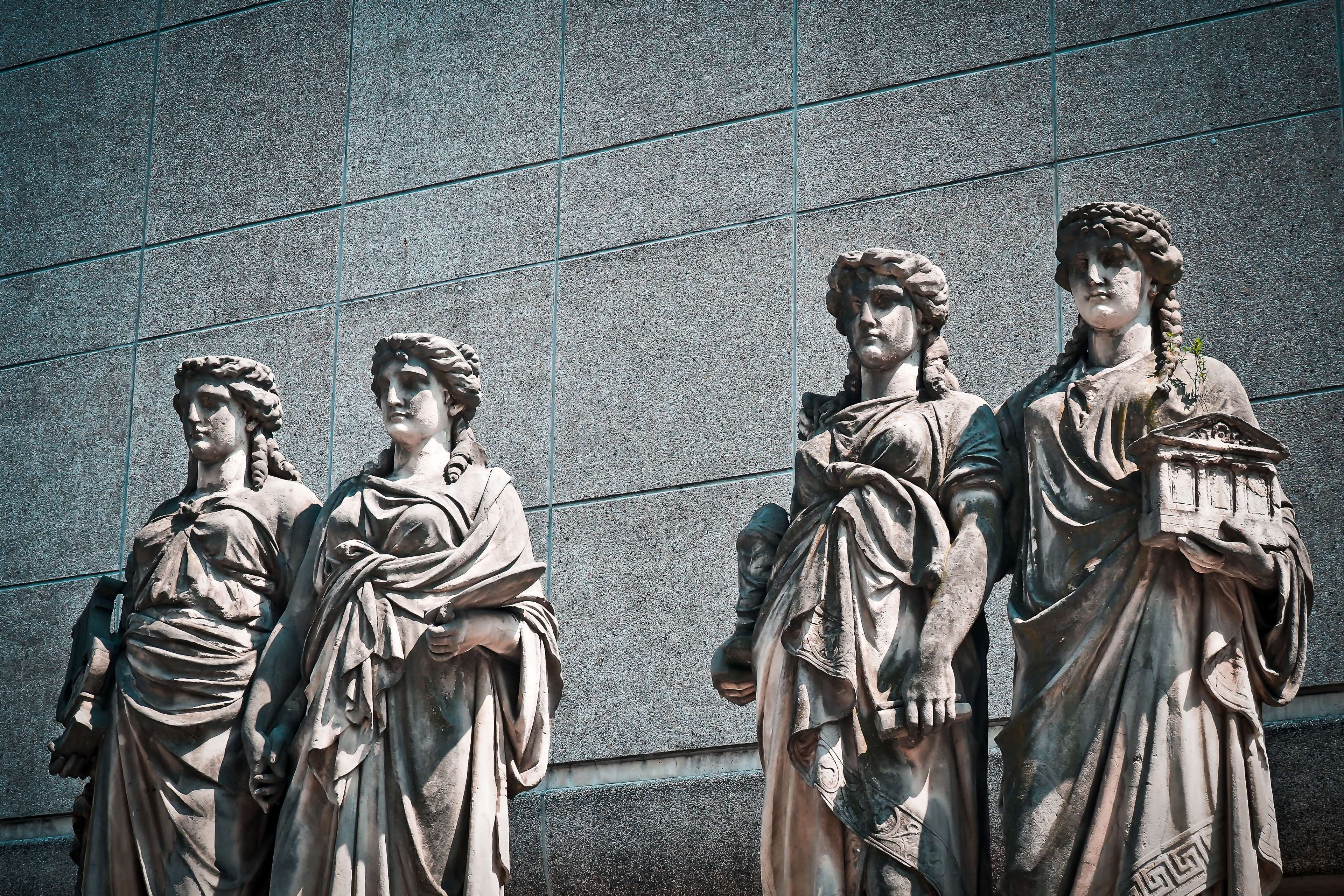 Four stone statues in front of a building HD Wallpaper