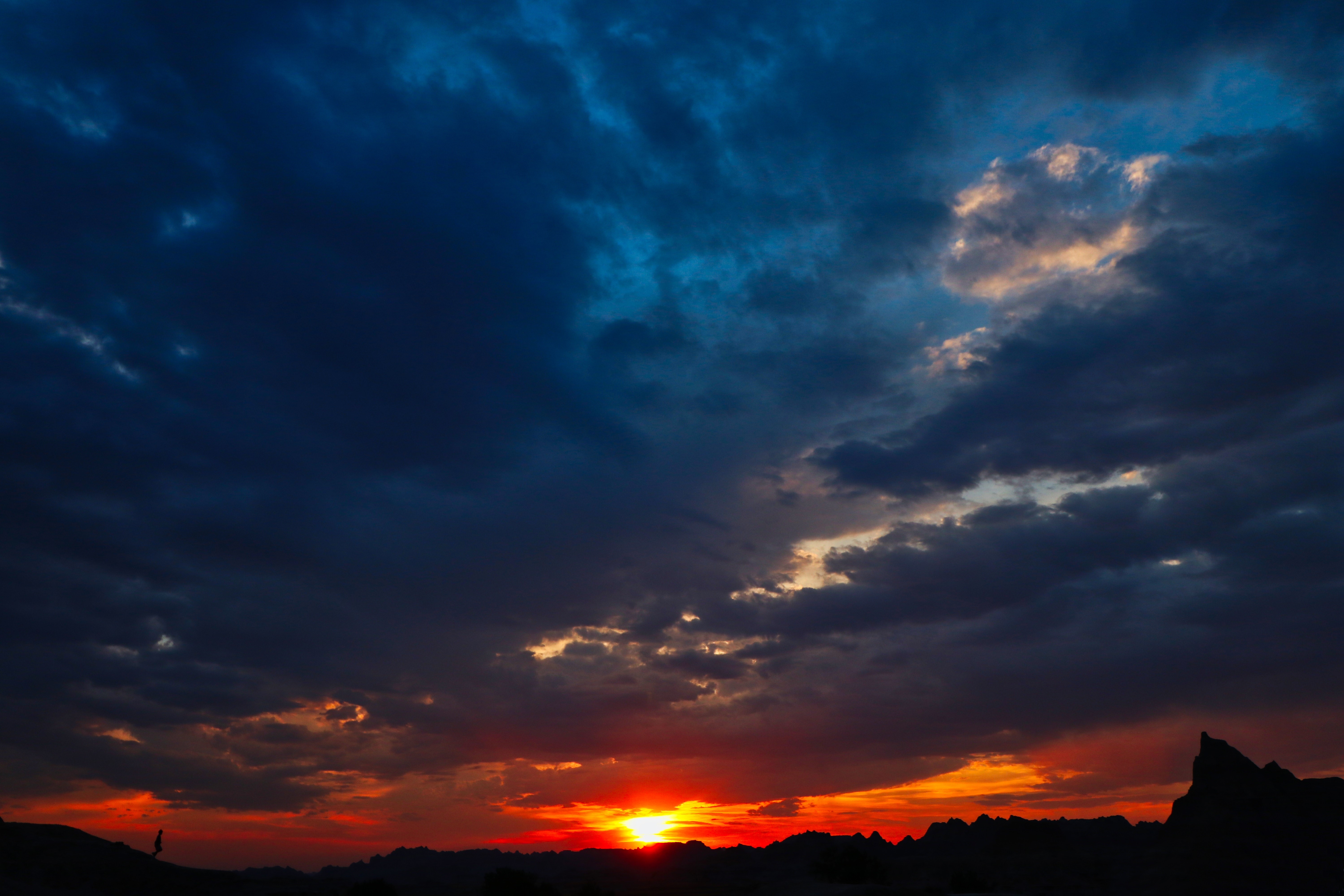 Silhouette of a person against a dramatic sunset sky HD Wallpaper