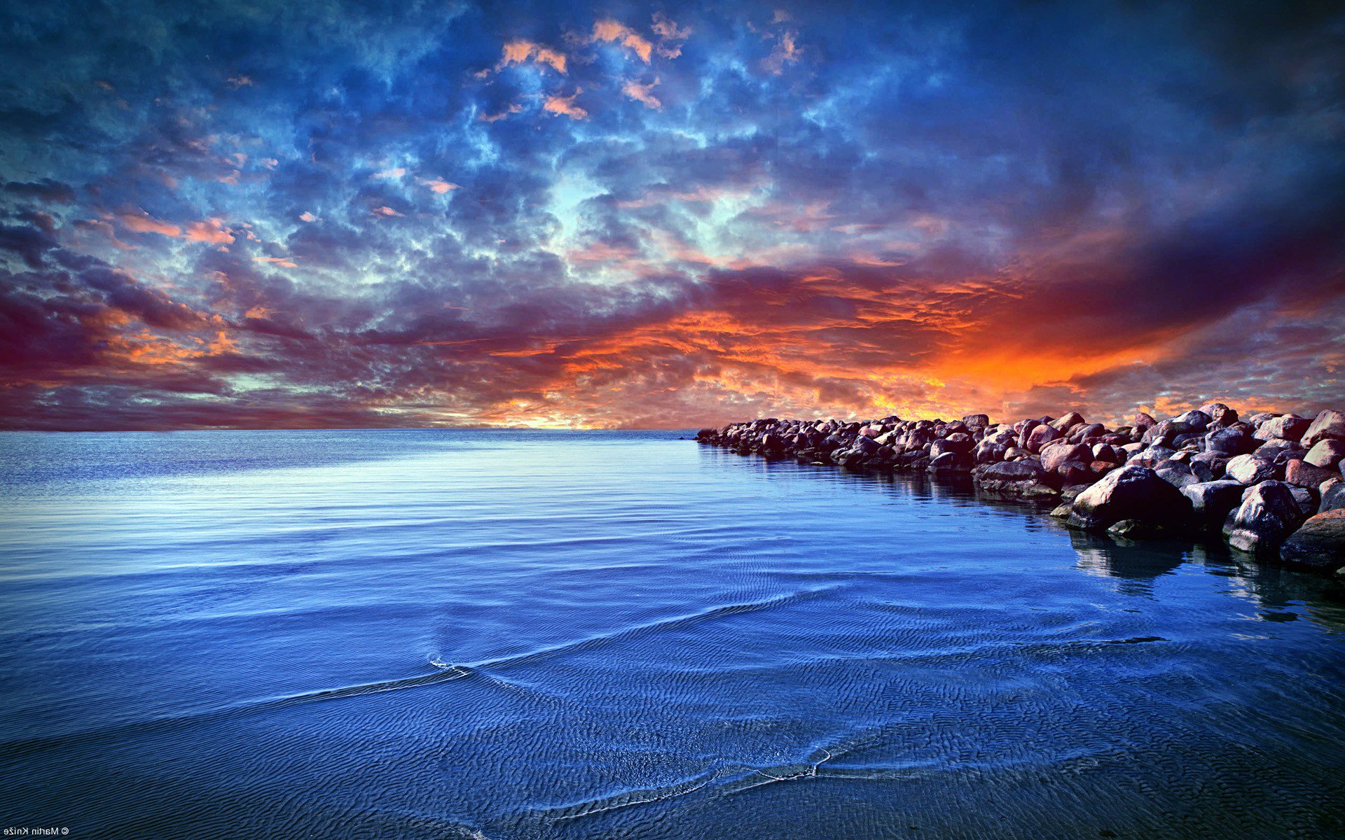 Dramatic sunset over the ocean with a rocky shore HD Wallpaper