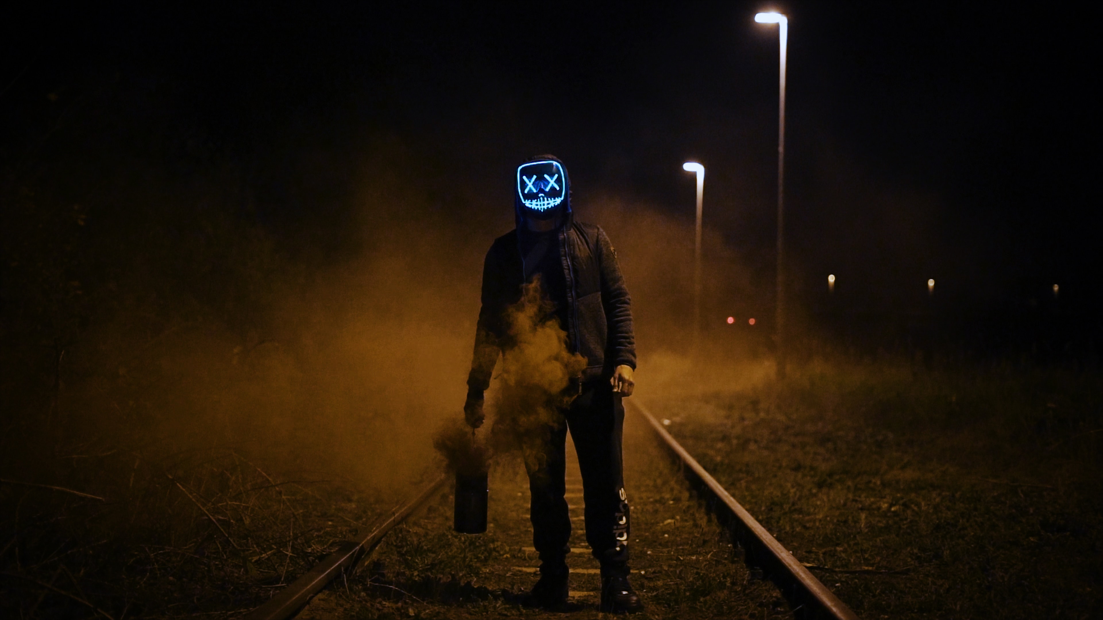 Man with glowing mask on railroad with smoke HD Wallpaper