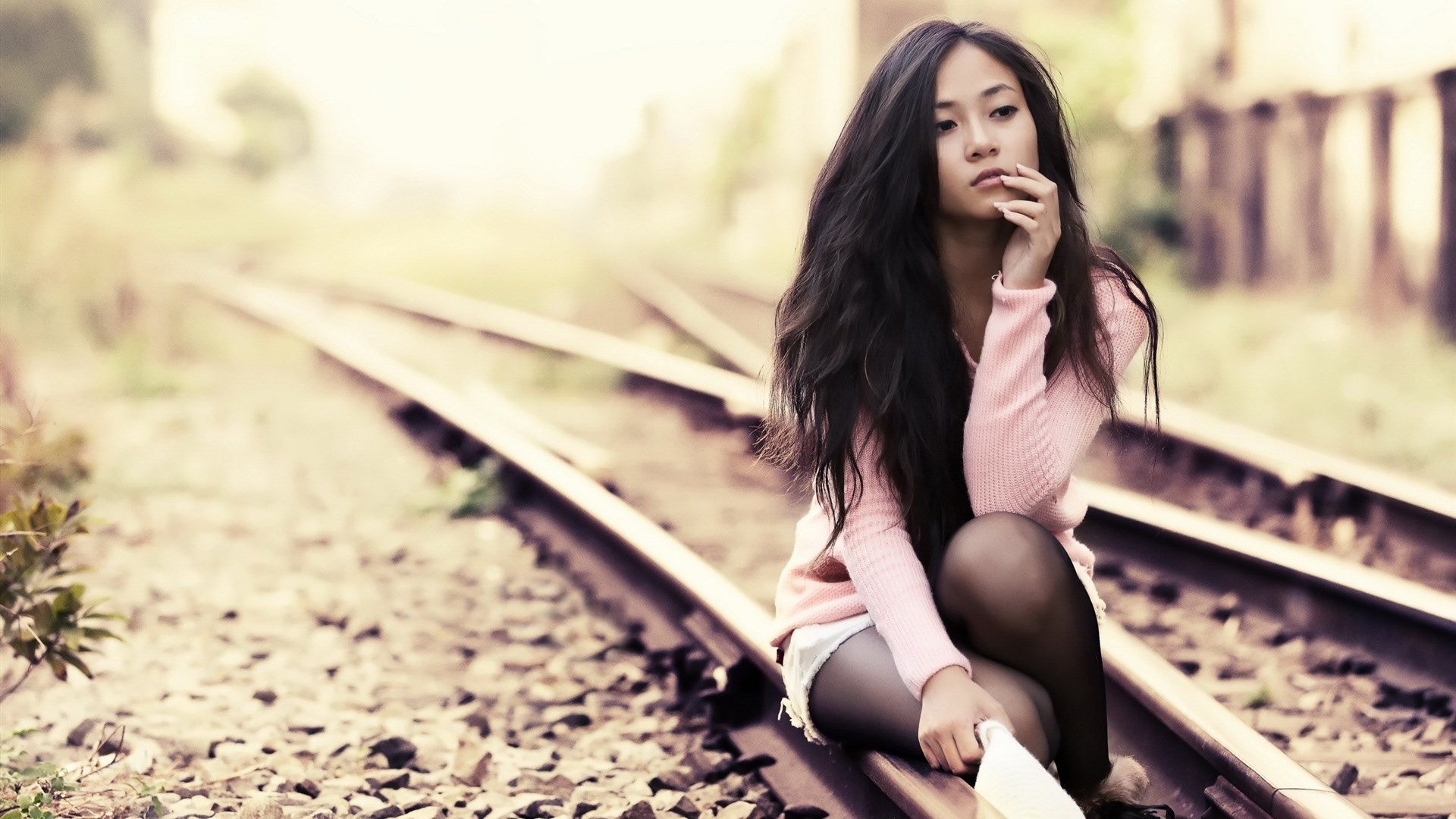 Young woman sitting on train tracks HD Wallpaper
